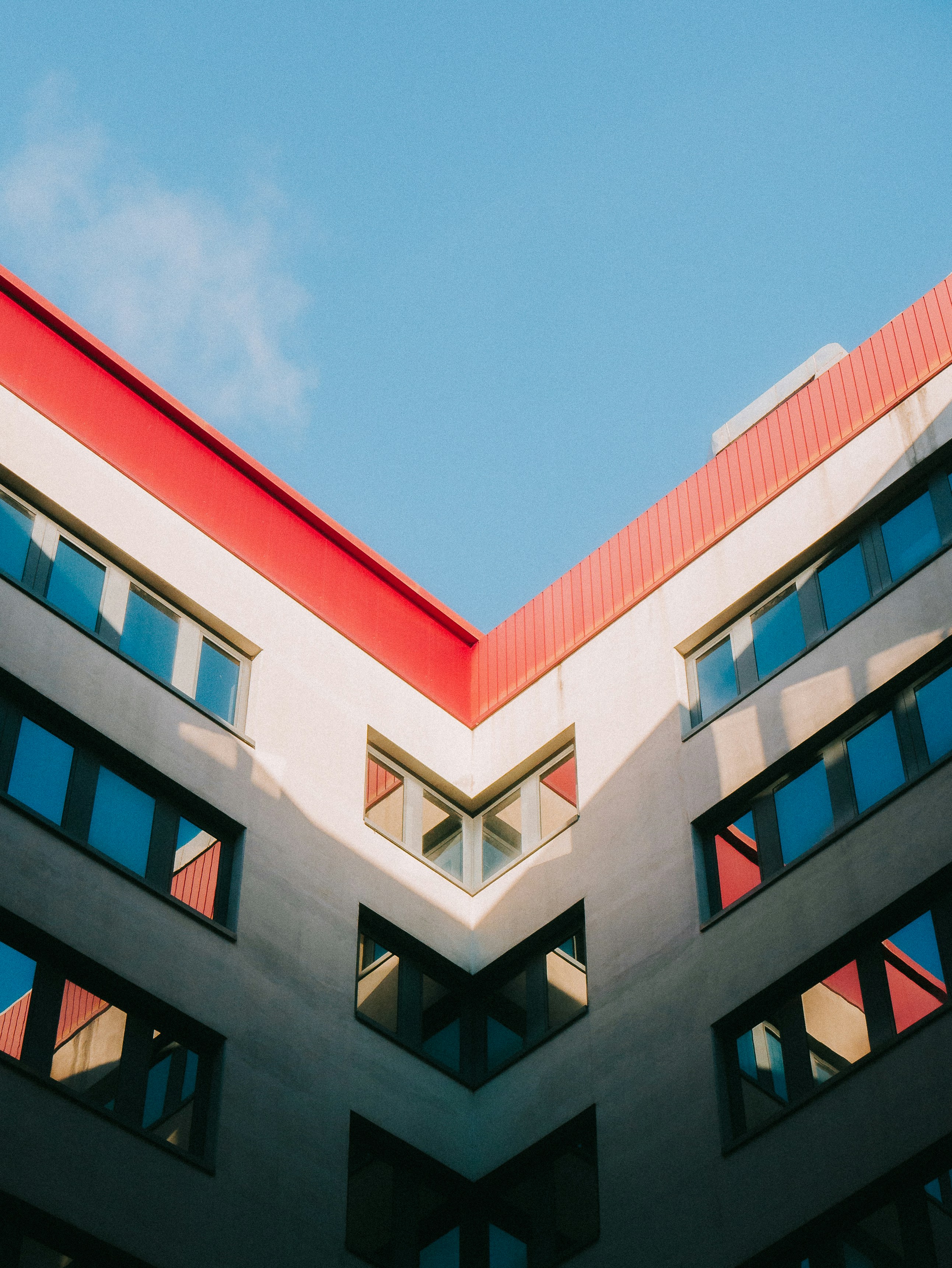 Modern building with red roof and blue sky.