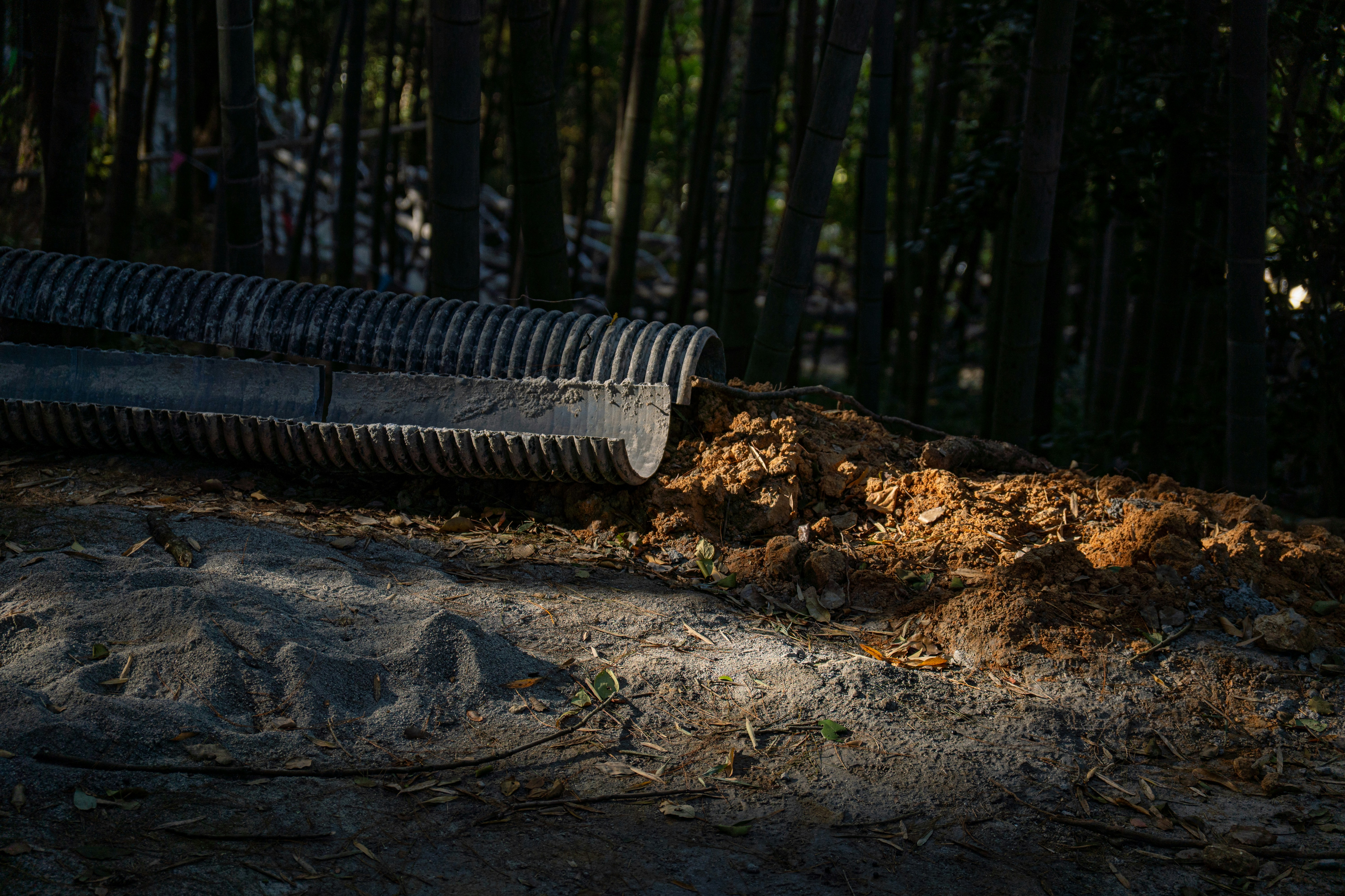 A drainage pipe empties dirt onto a path