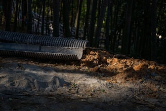 A drainage pipe empties dirt onto a path