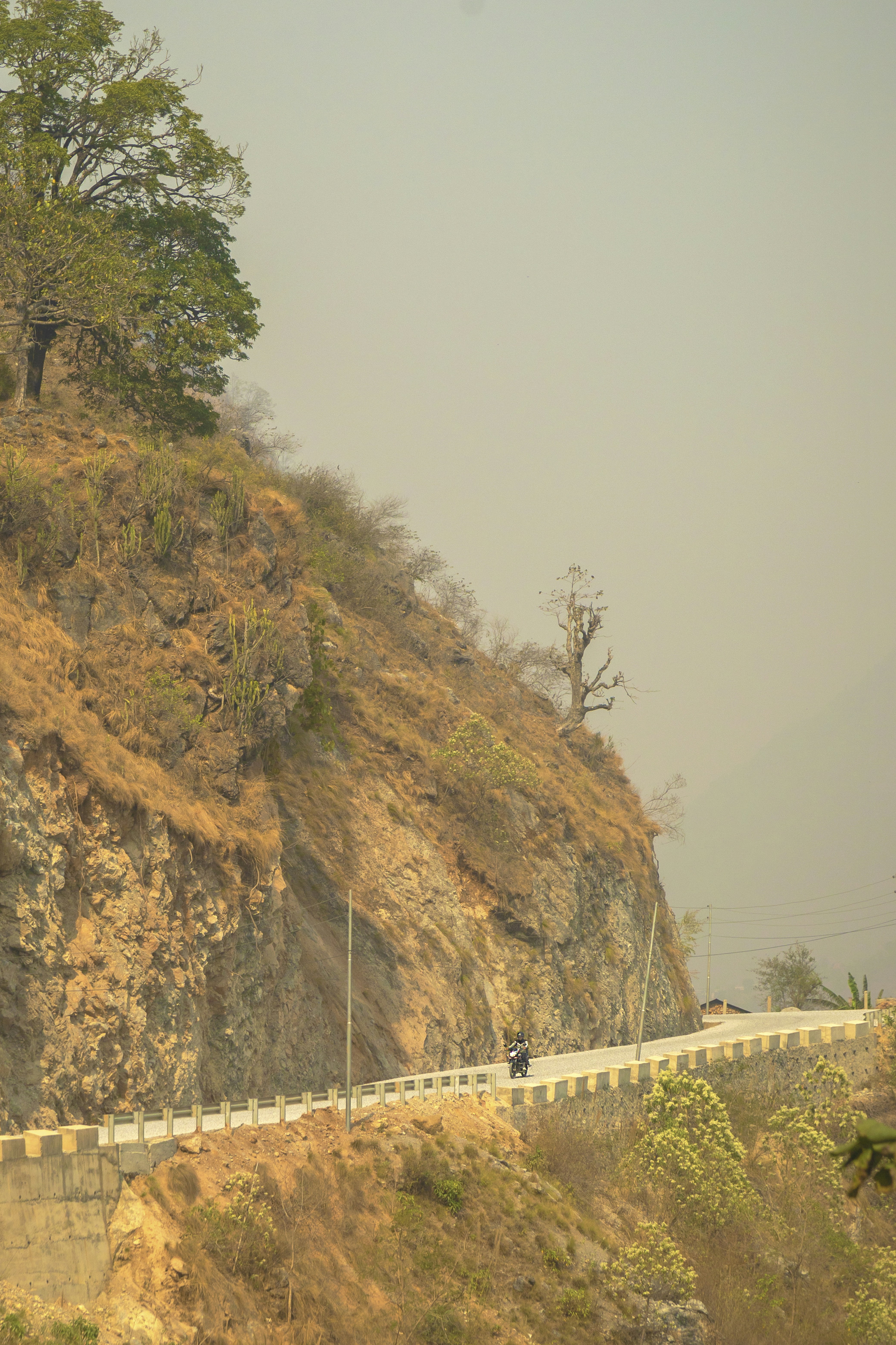 Motorcyclist on a winding road along a rocky mountainside