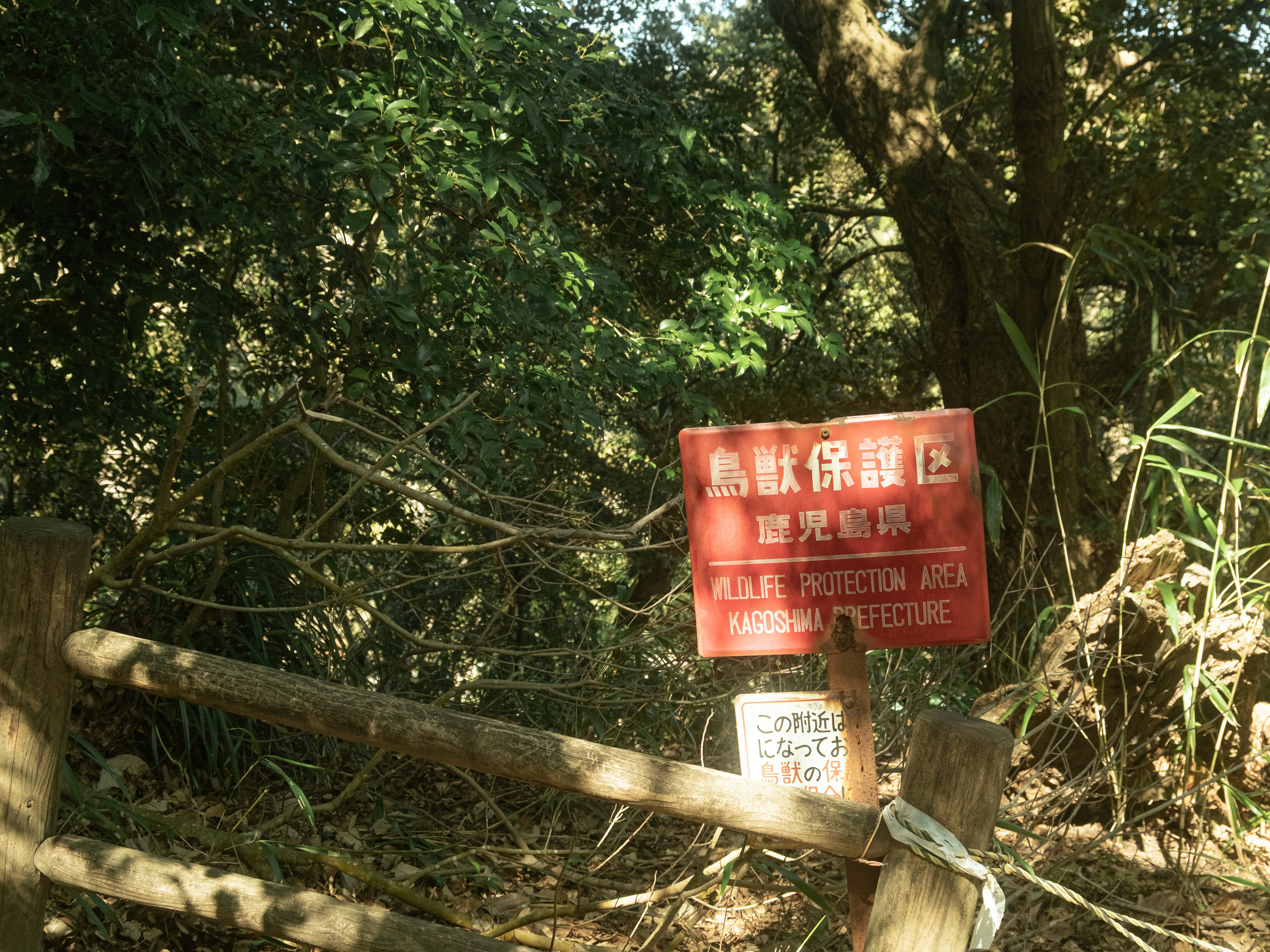 Red sign in a forest with text incription.