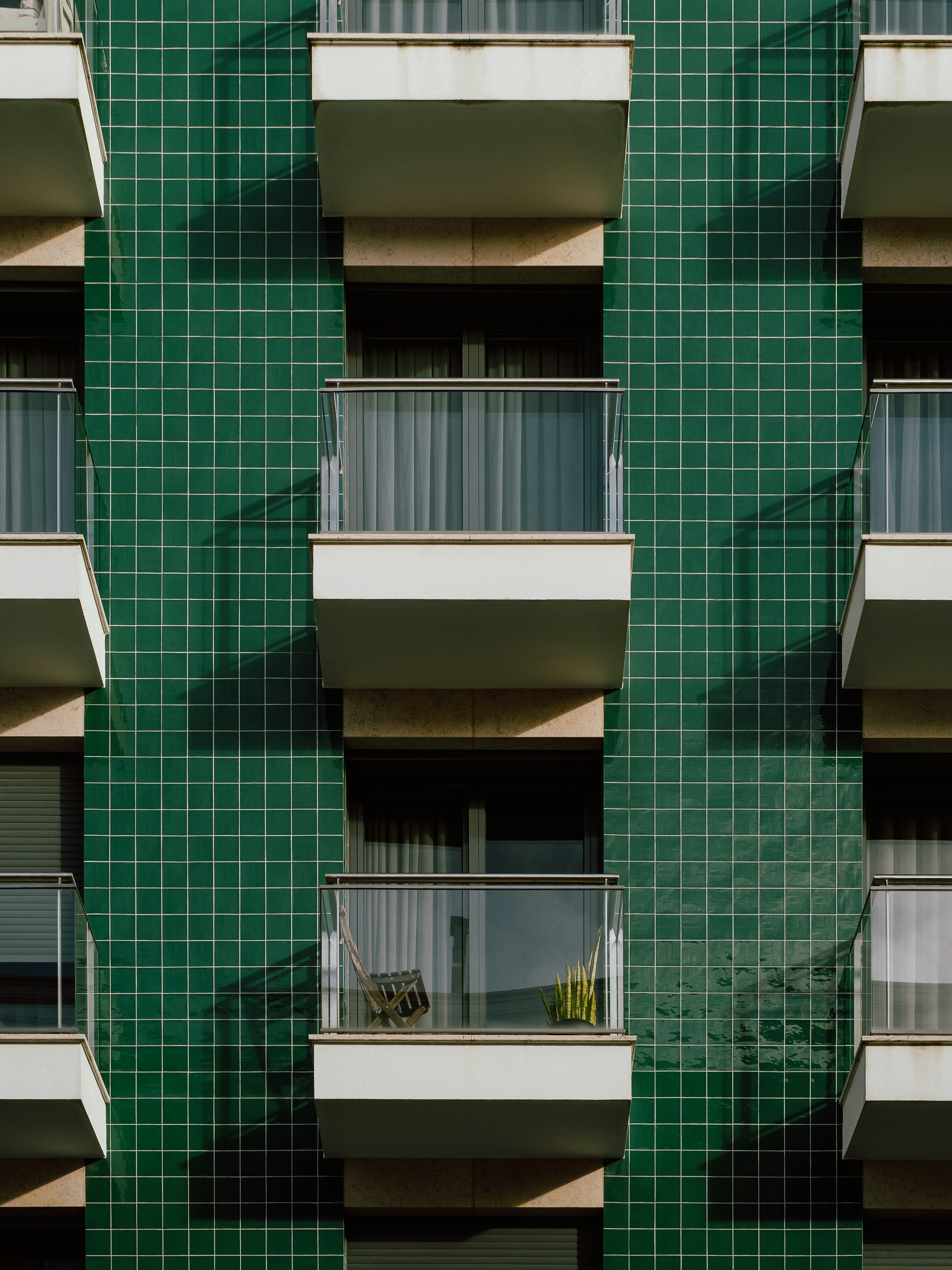 Balkone auf einer grün gefliesten Gebäudefassade