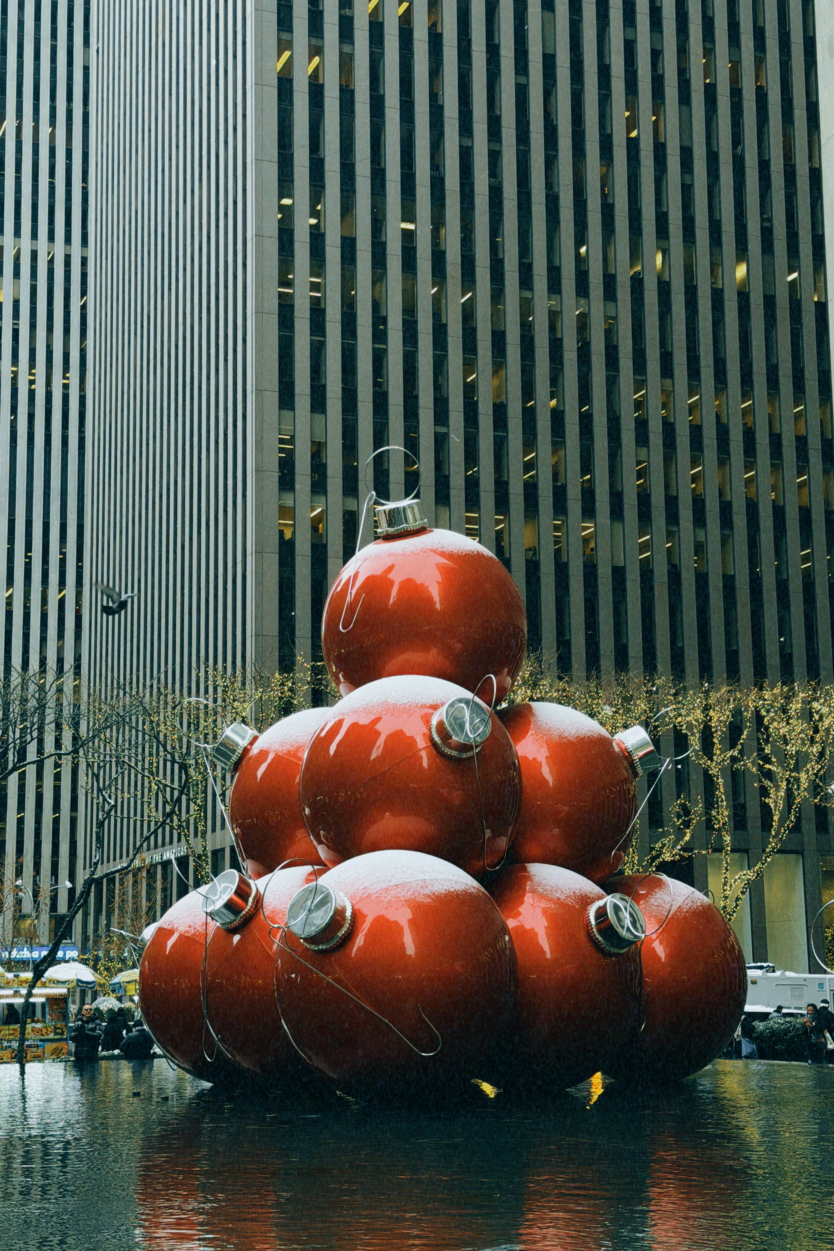 Giant red christmas ornaments stacked in front of buildings