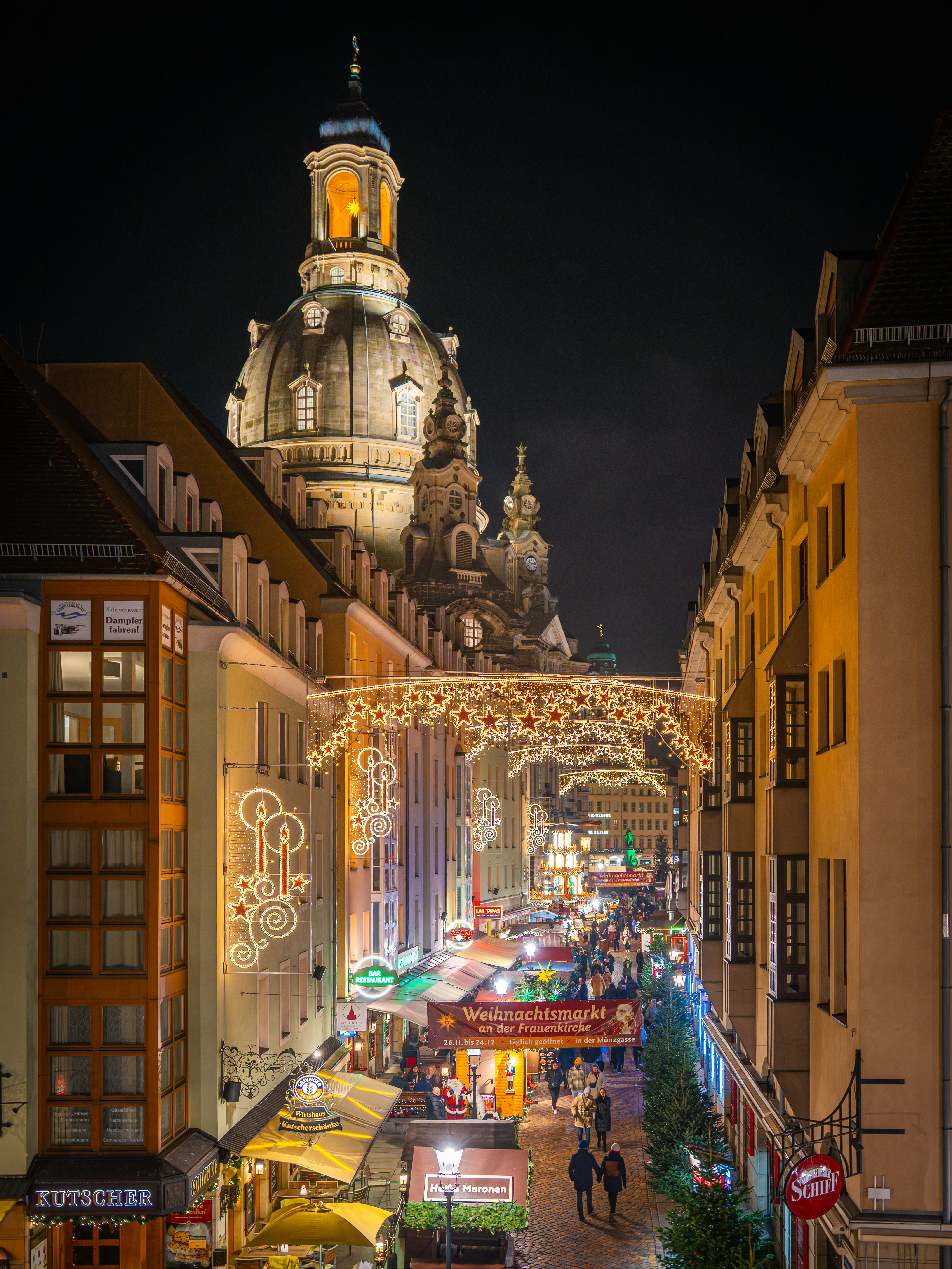 Festive street decorated with christmas lights at night.