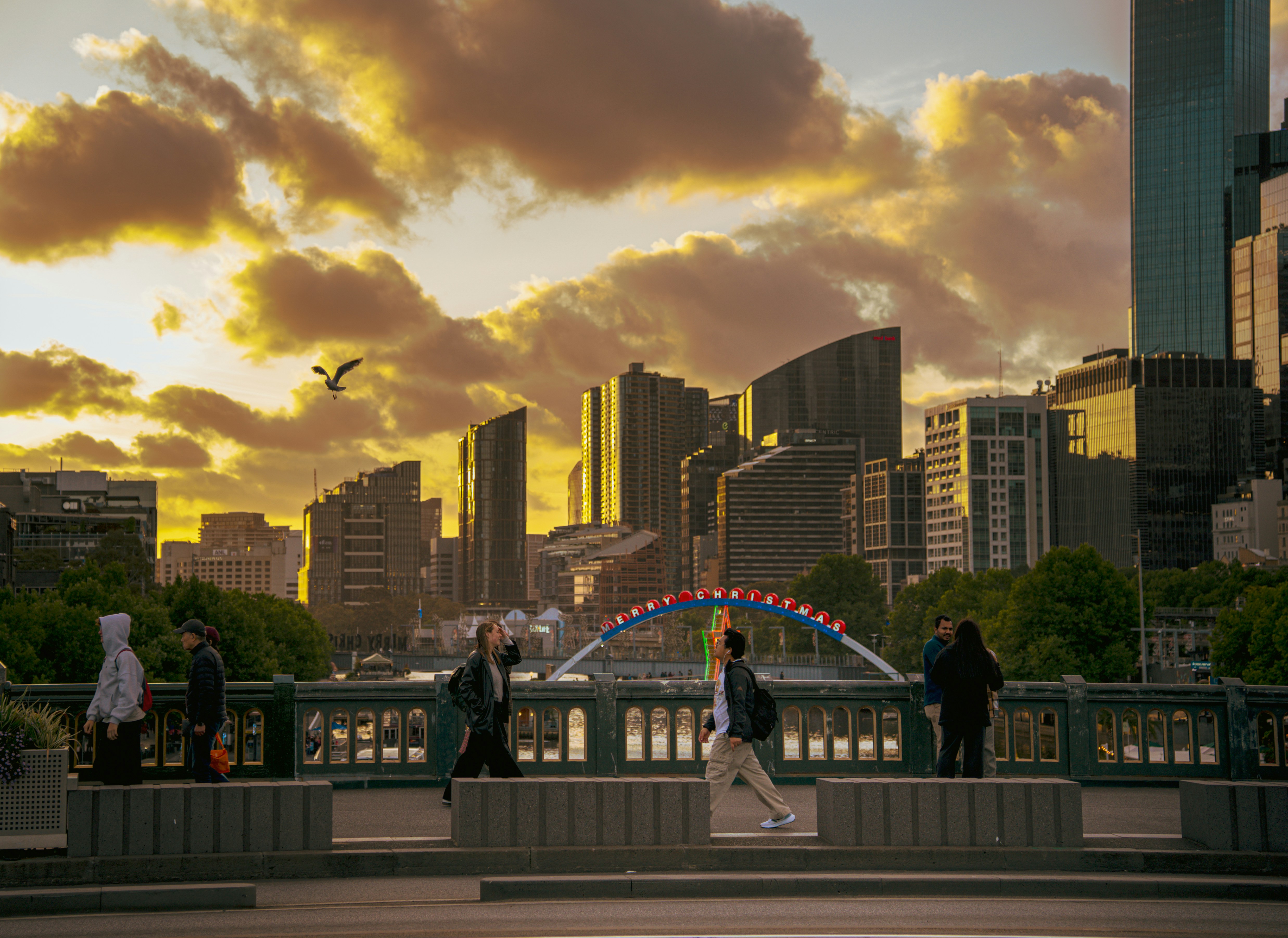 City skyline at sunset with people on a bridge.