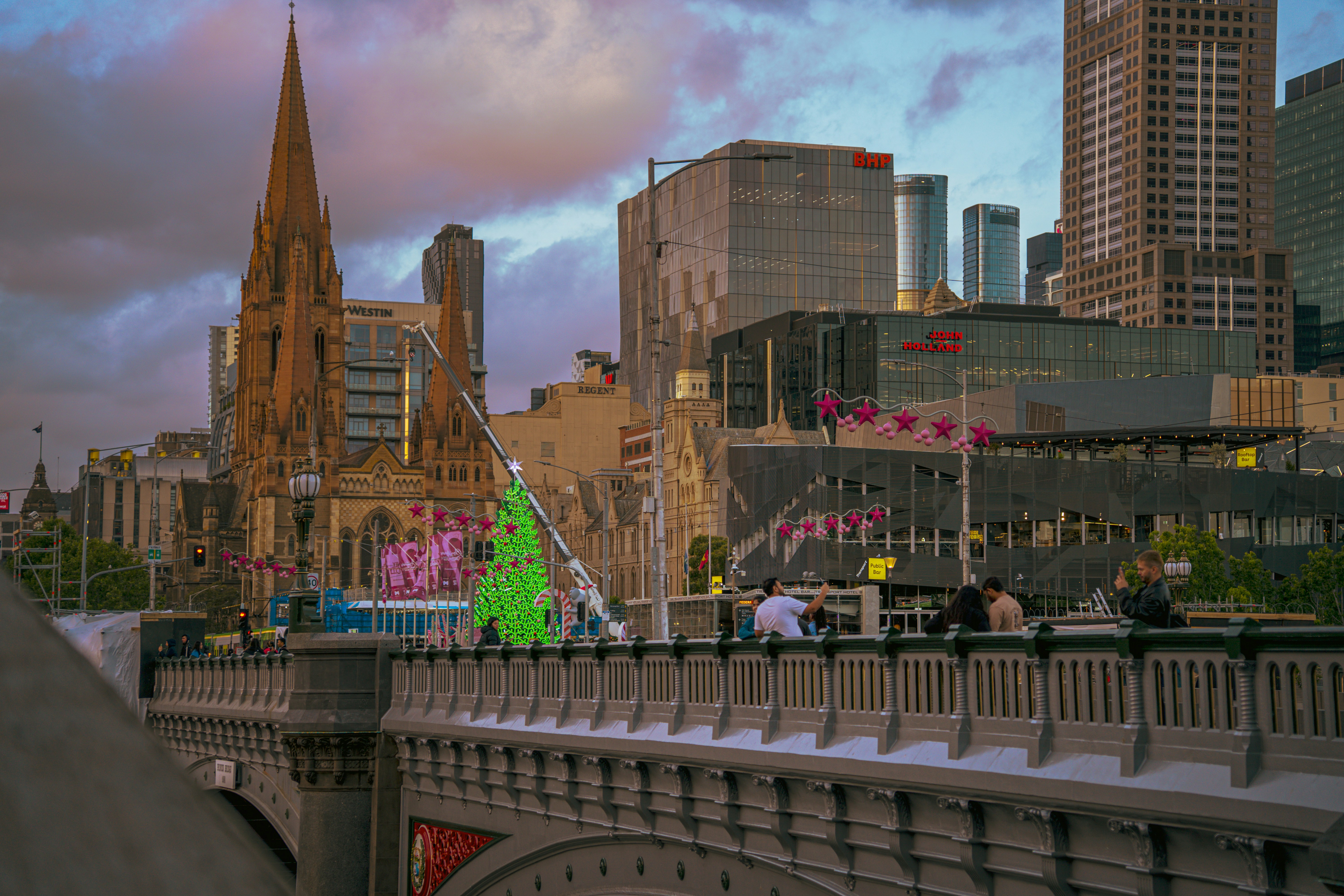 City skyline with a bridge and church spire at sunset