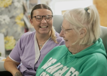 Two women laughing together indoors.