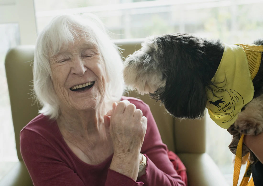 An older woman laughing with a dog, representing the quality of life that non-economic damages recognize
