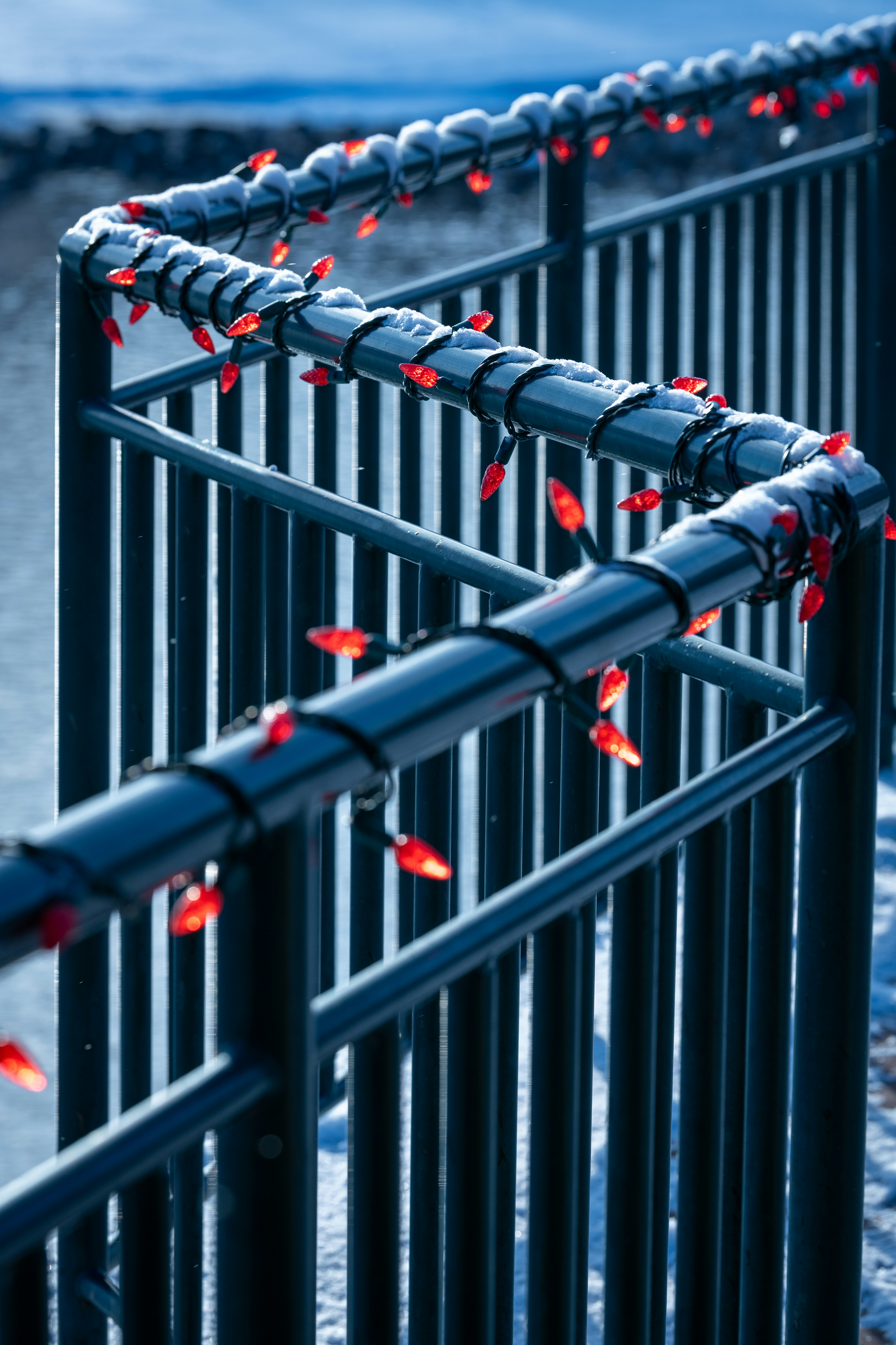 Rote Lichter umschlangen ein dunkles Metallgeländer draußen.