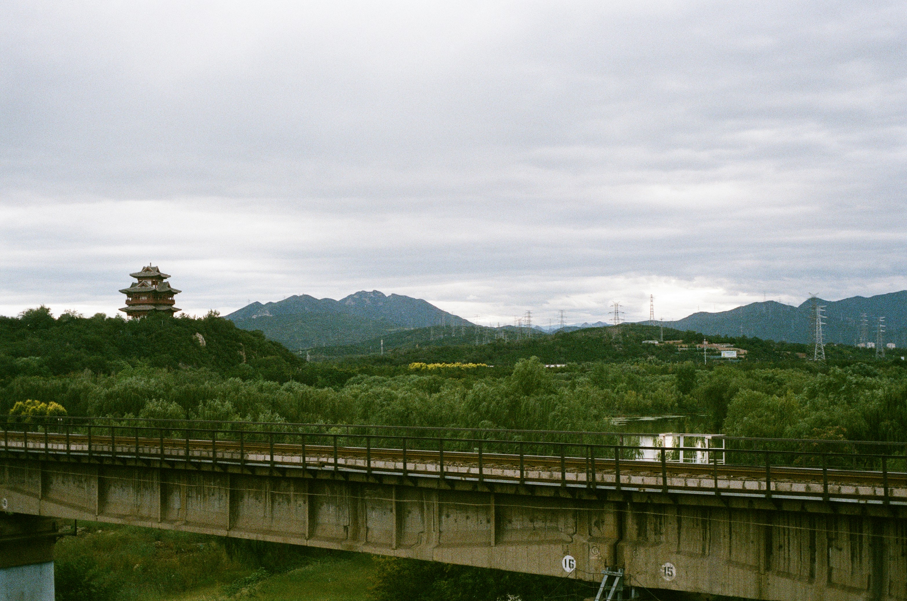 Train crossing a bridge with distant mountains.