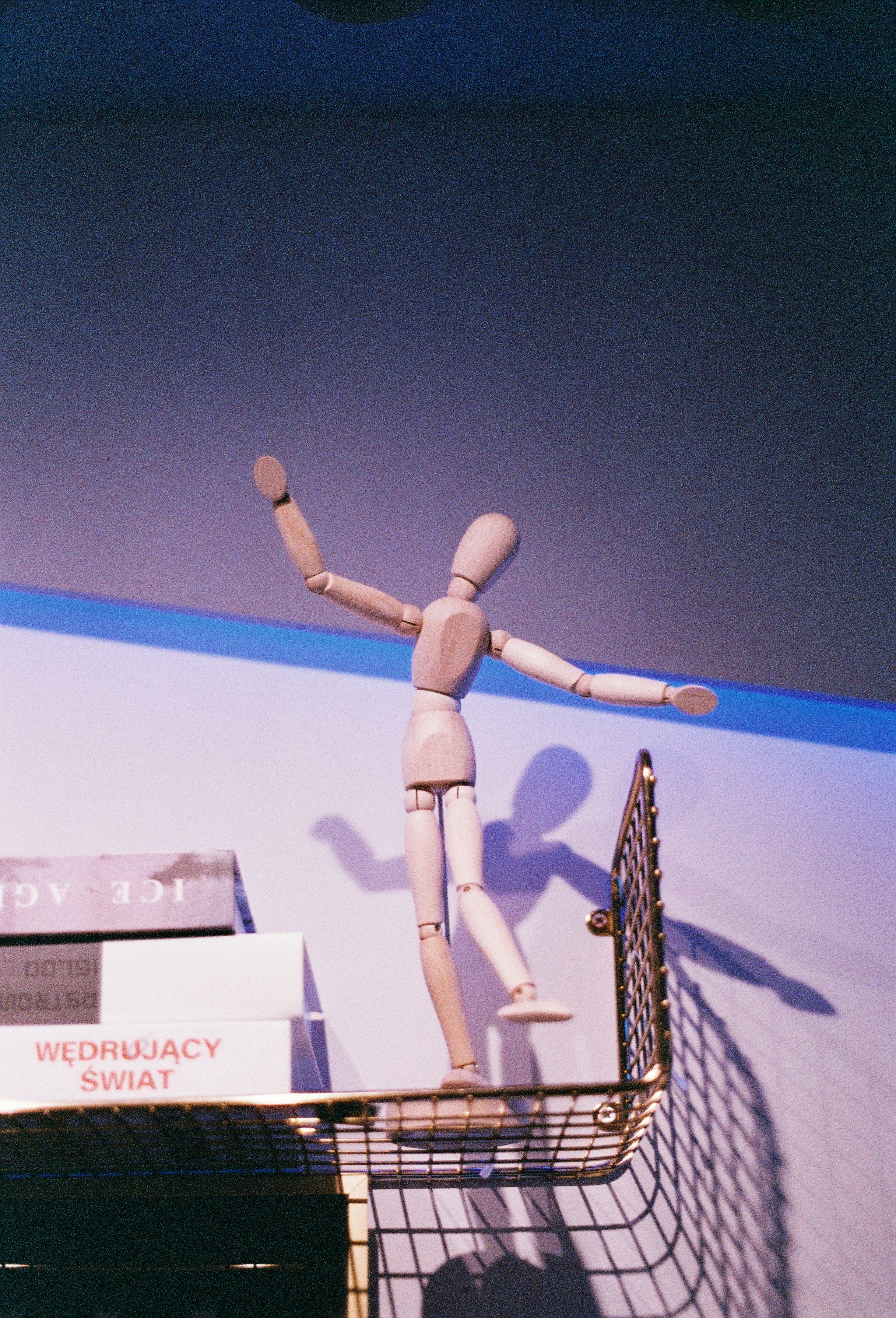 Wooden mannequin balancing on a shelf.