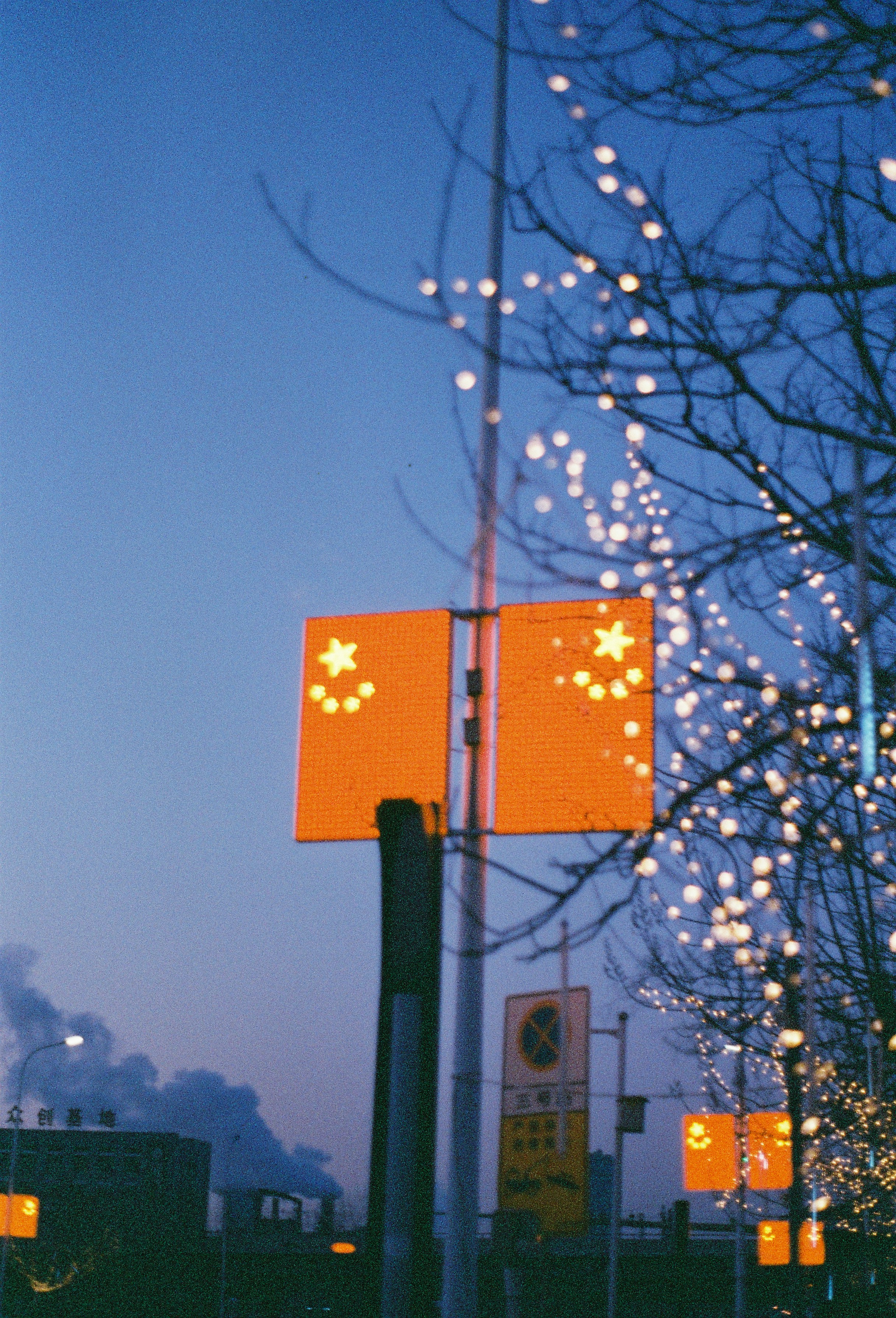 Chinese flags illuminated at dusk with city lights.