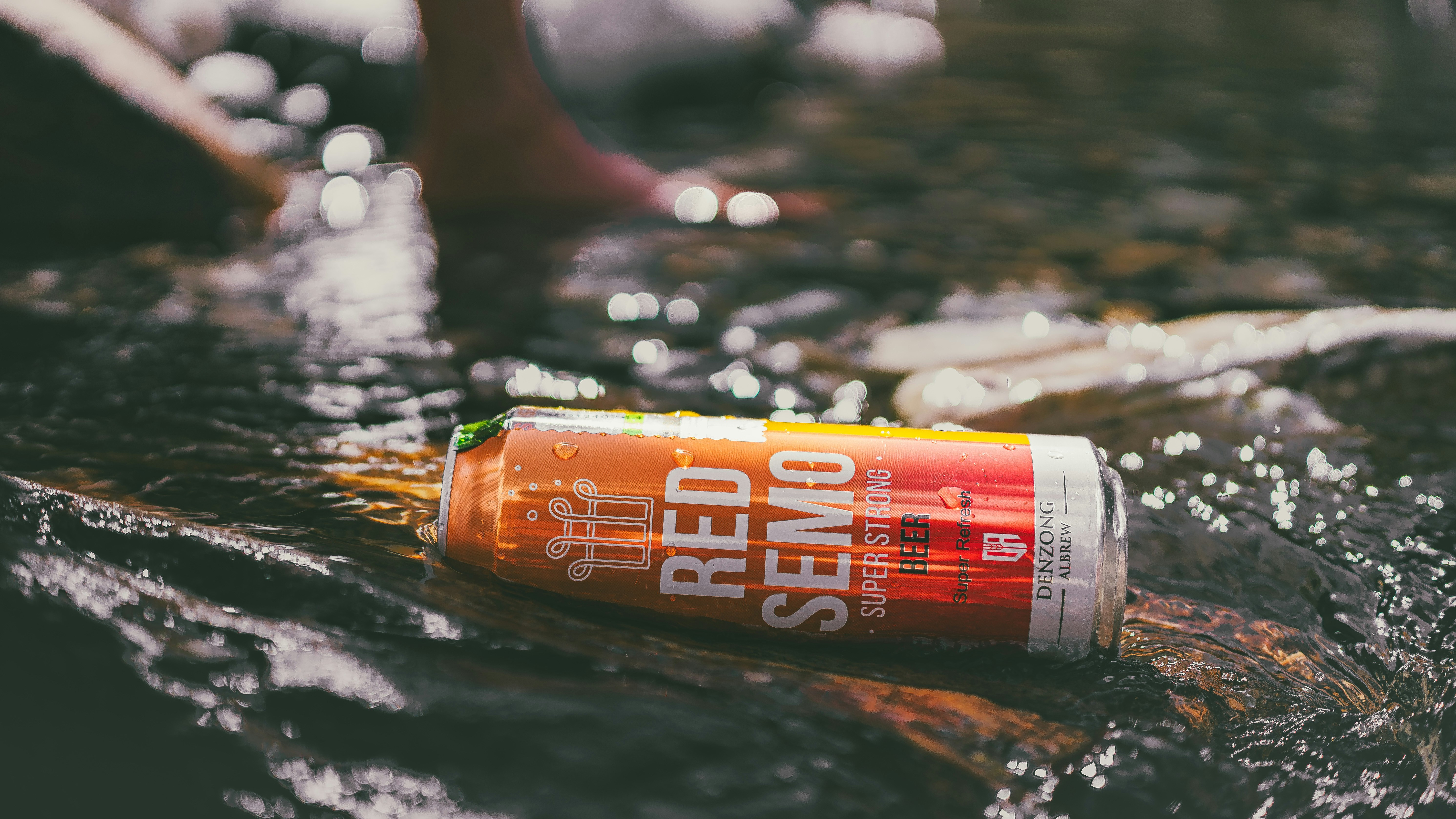 A can of red semo beer floats in a stream.