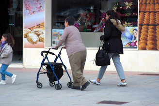 People walking on a sidewalk next to shops.
