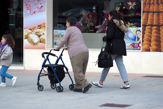 People walking on a sidewalk next to shops.
