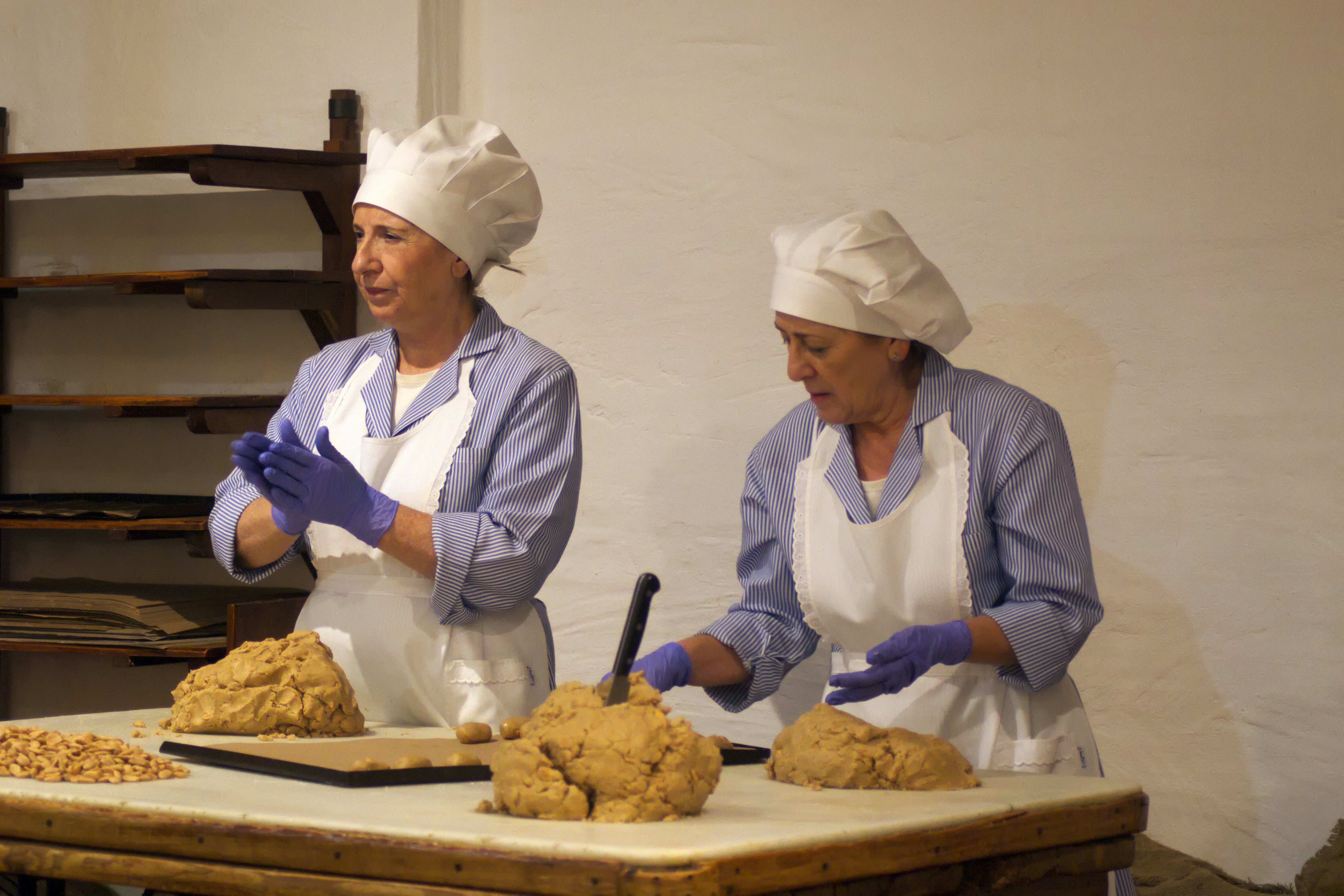 Two women in baker hats preparing dough