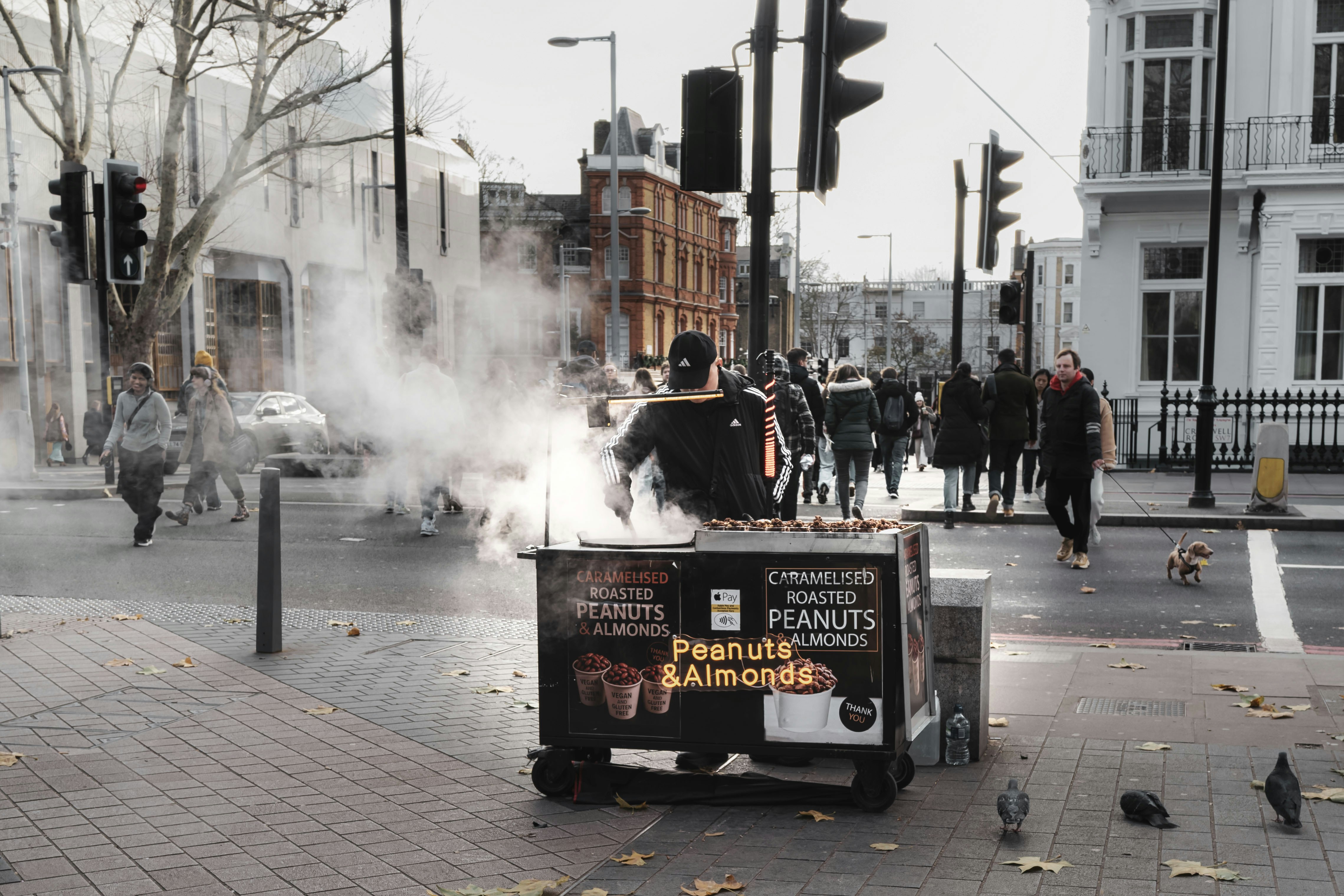 Vendeur ambulant vendant des noix grillées depuis un chariot.
