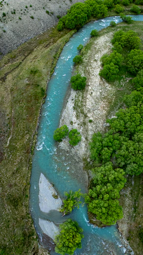 A winding turquoise river flows through a green, mountainous landscape.