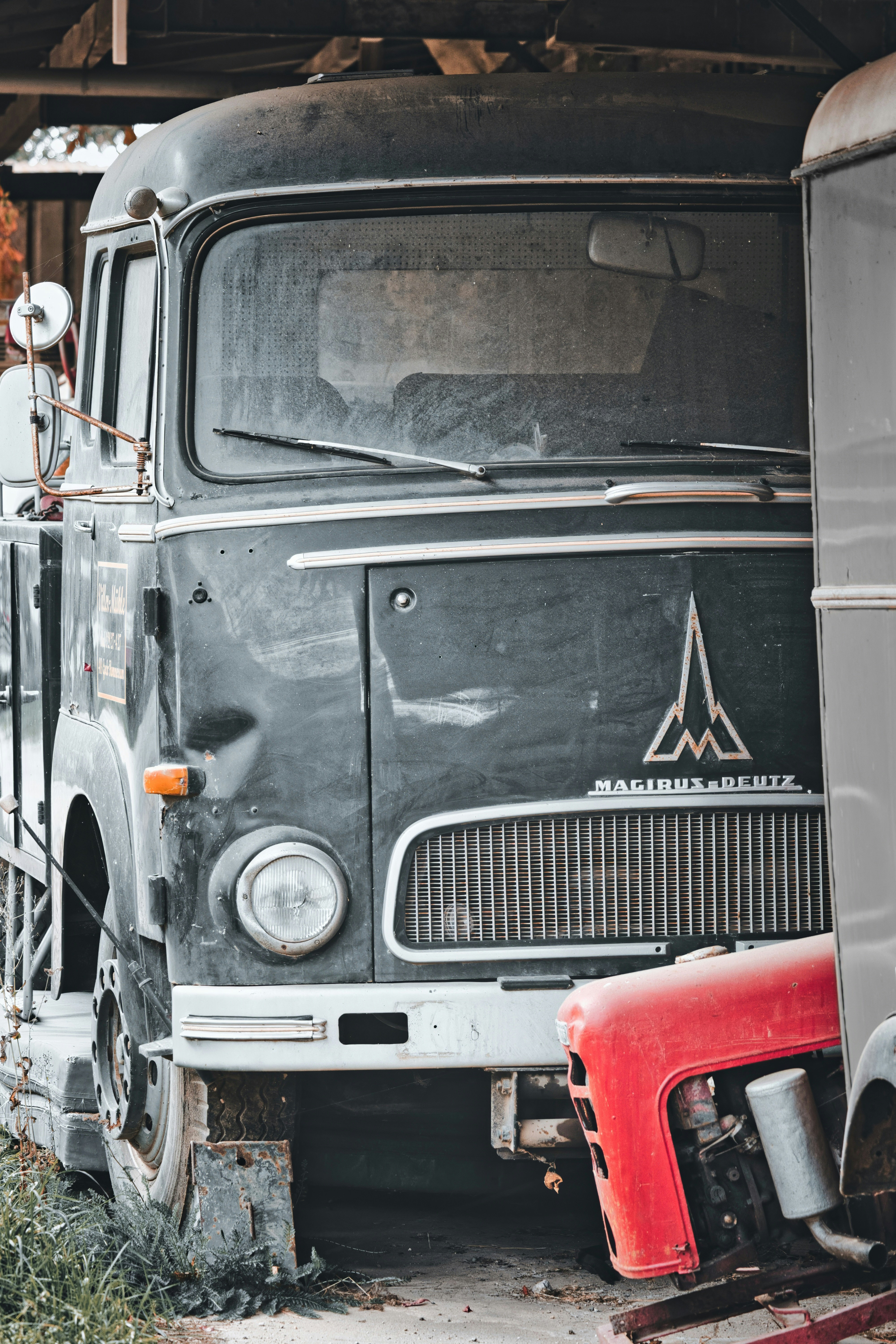 Old black truck with a red tractor part.