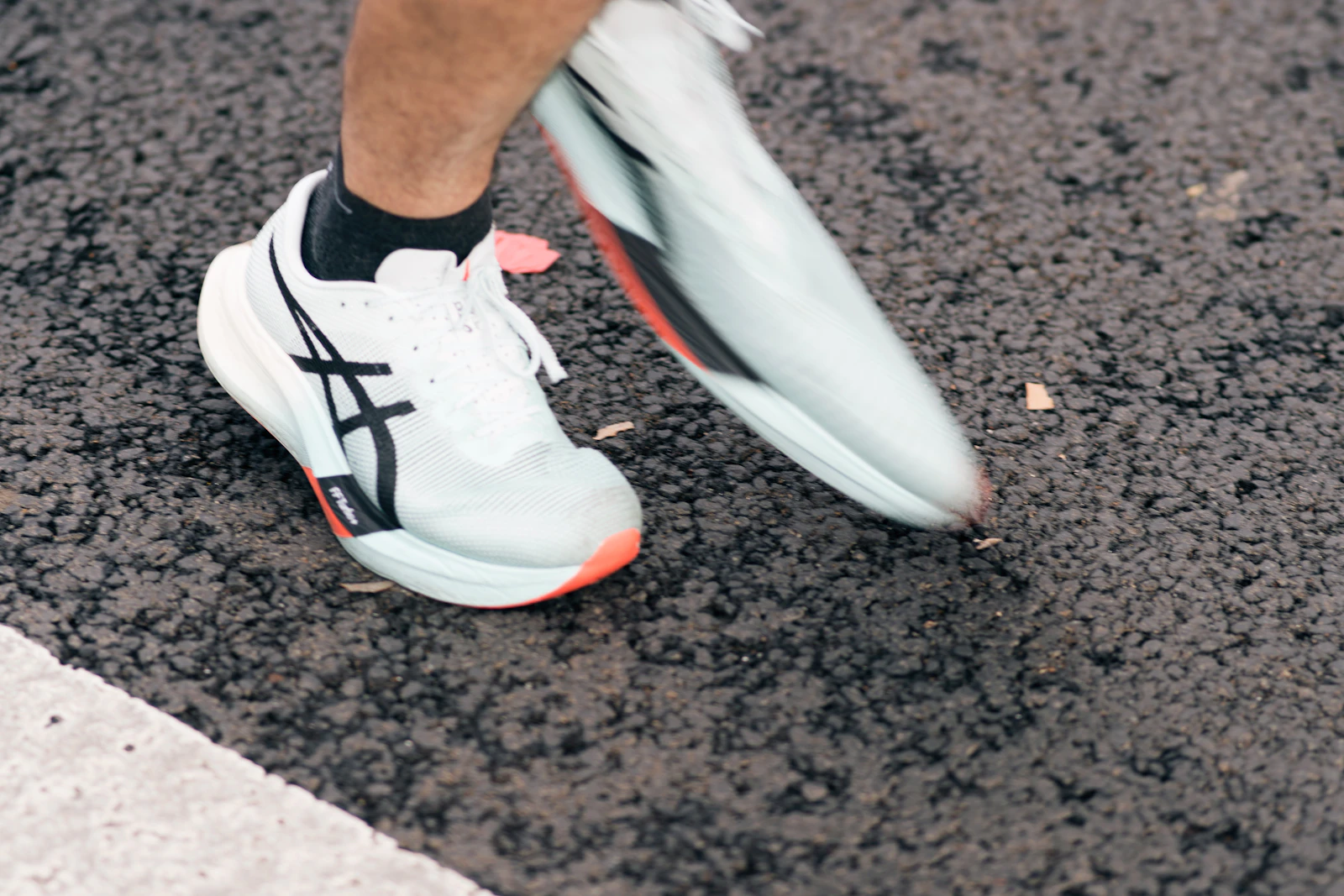 A runner's feet in white running shoes on the pavement