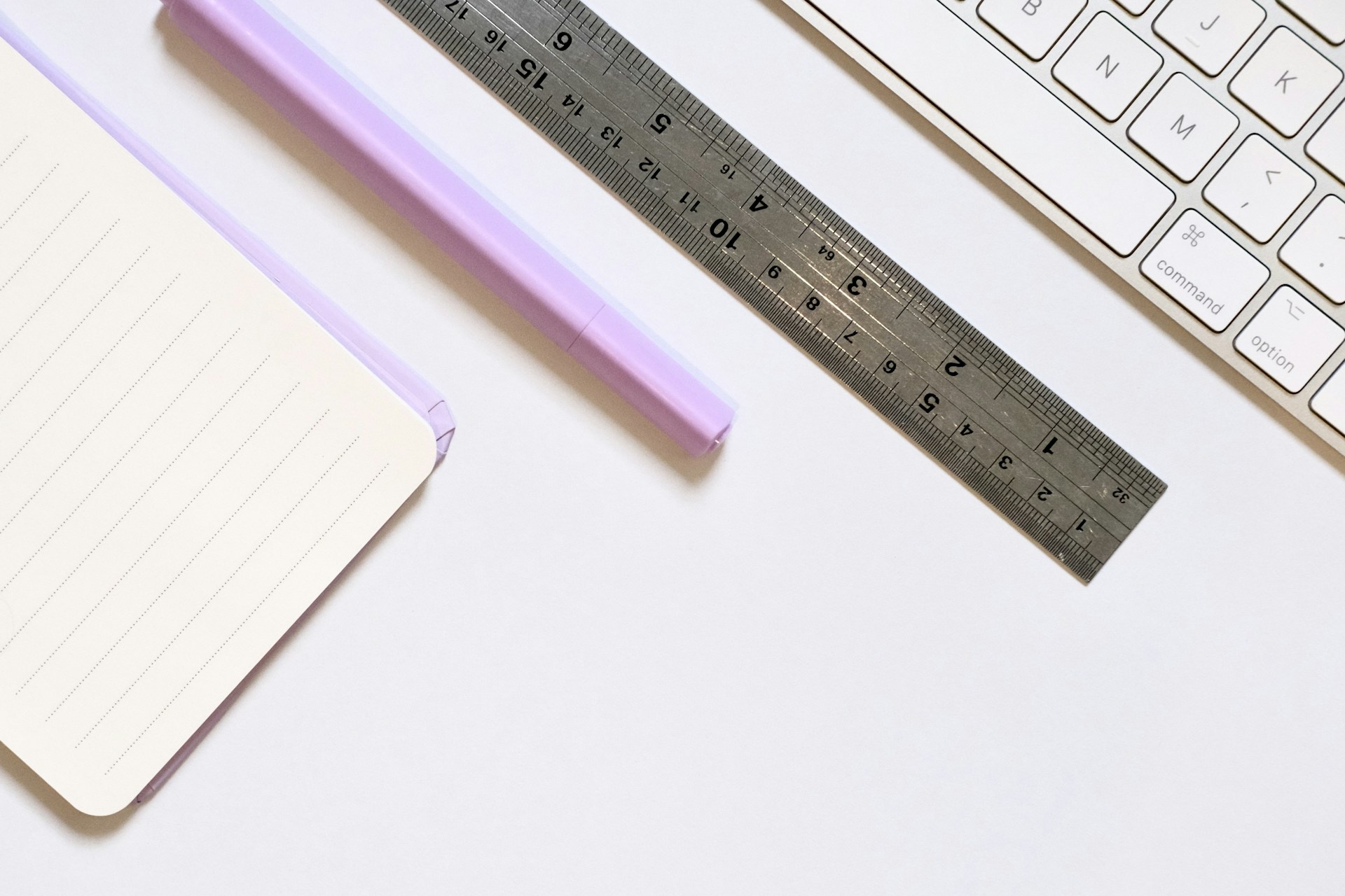 Notebook, ruler, and keyboard on white surface