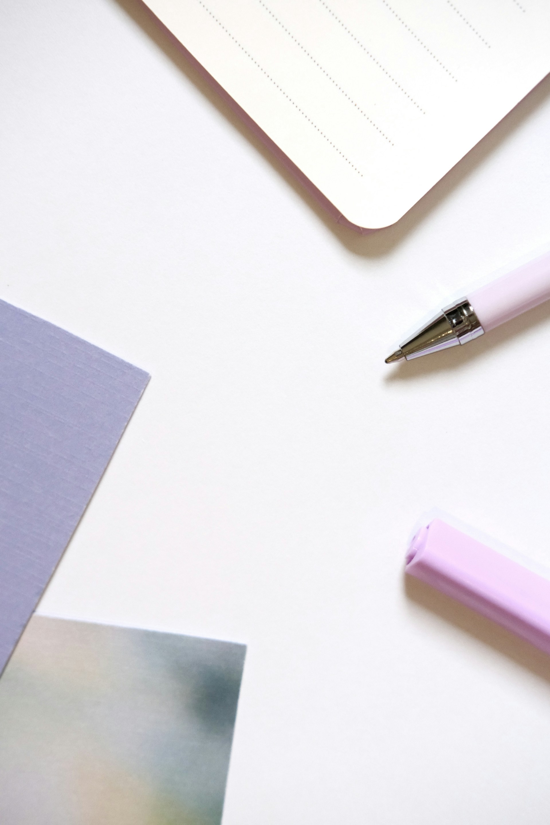 A pink pen, notebook, and sticky notes on white background.