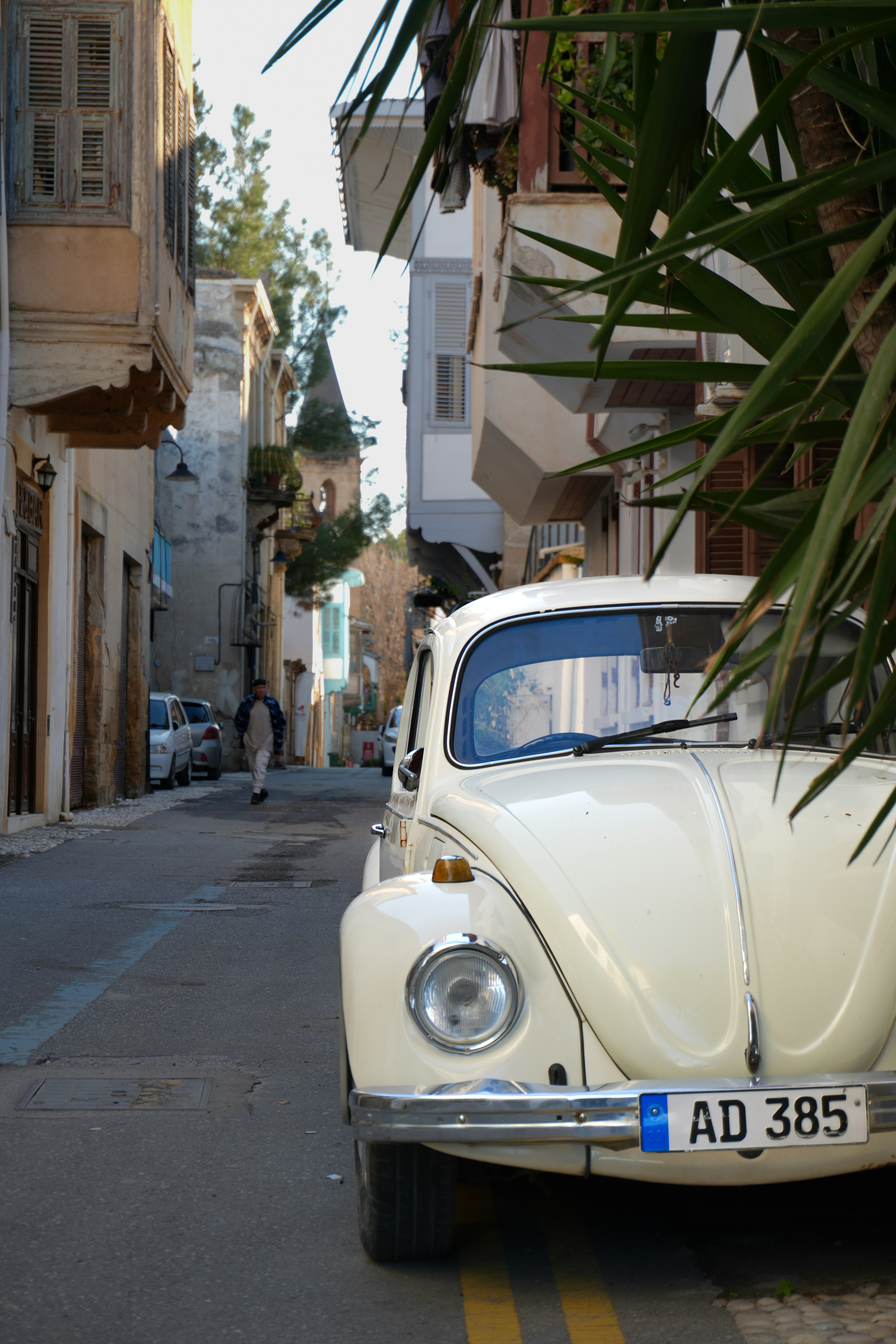 White vintage car parked on a narrow street.