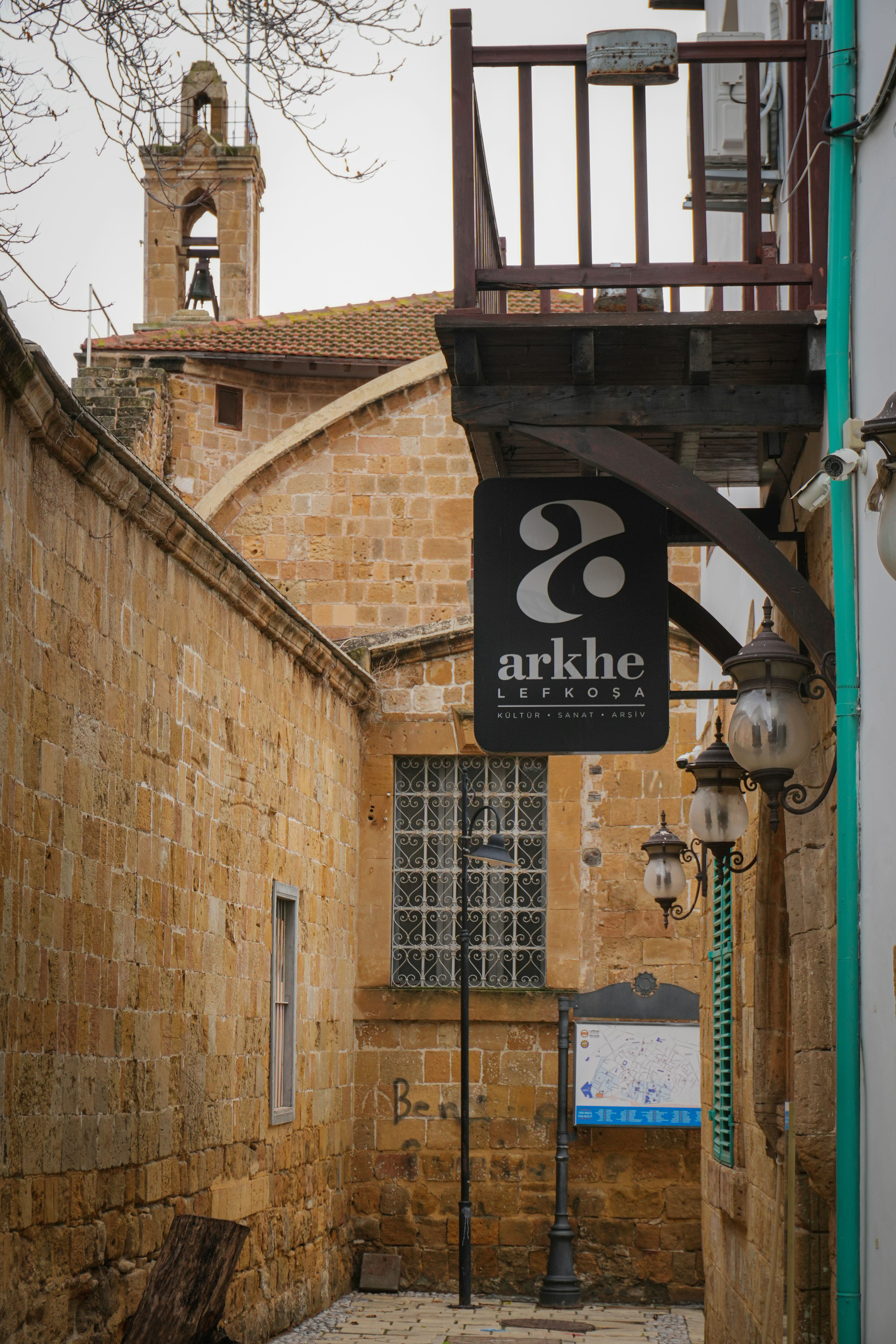Narrow cobblestone street with stone buildings and sign.