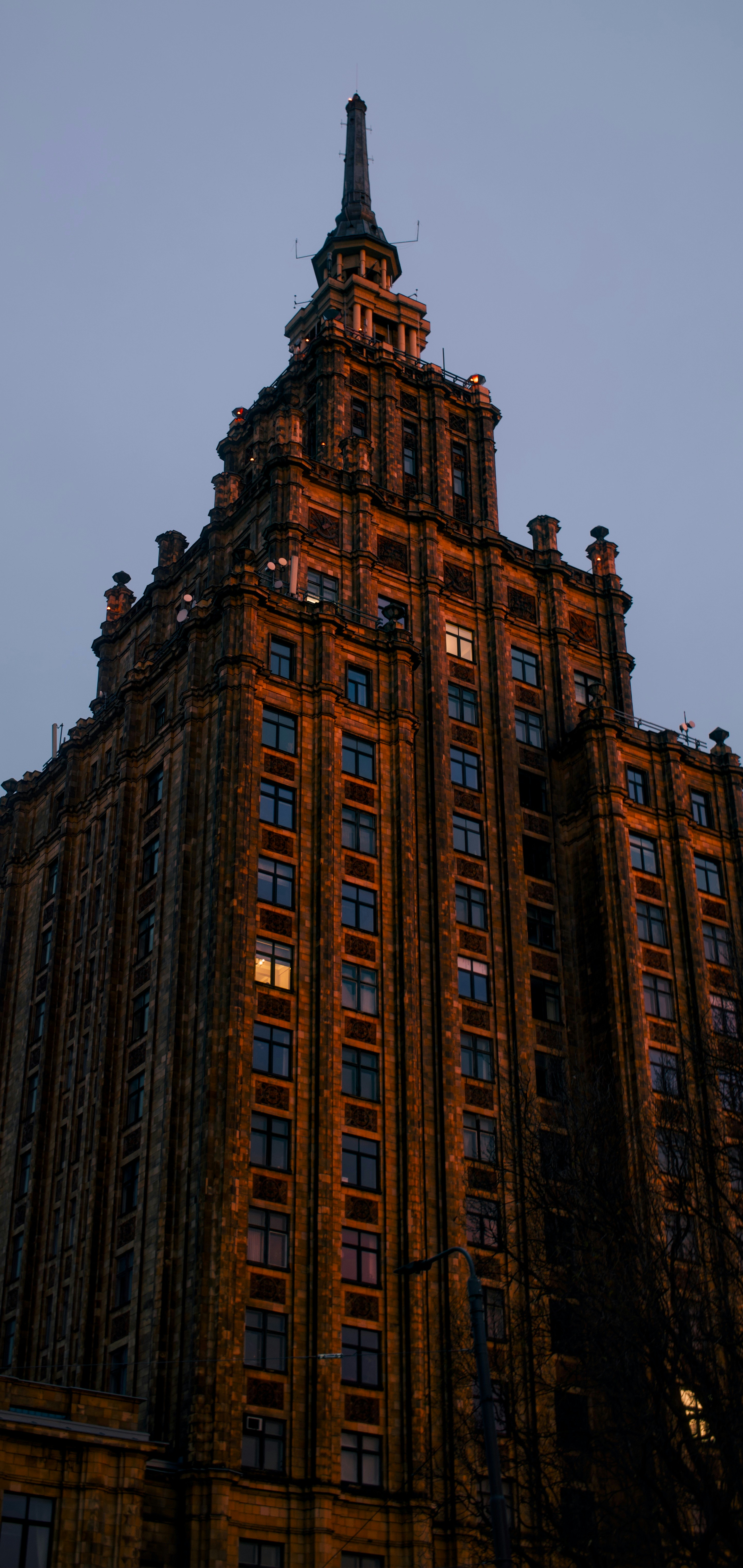 Tall ornate building with glowing windows at dusk