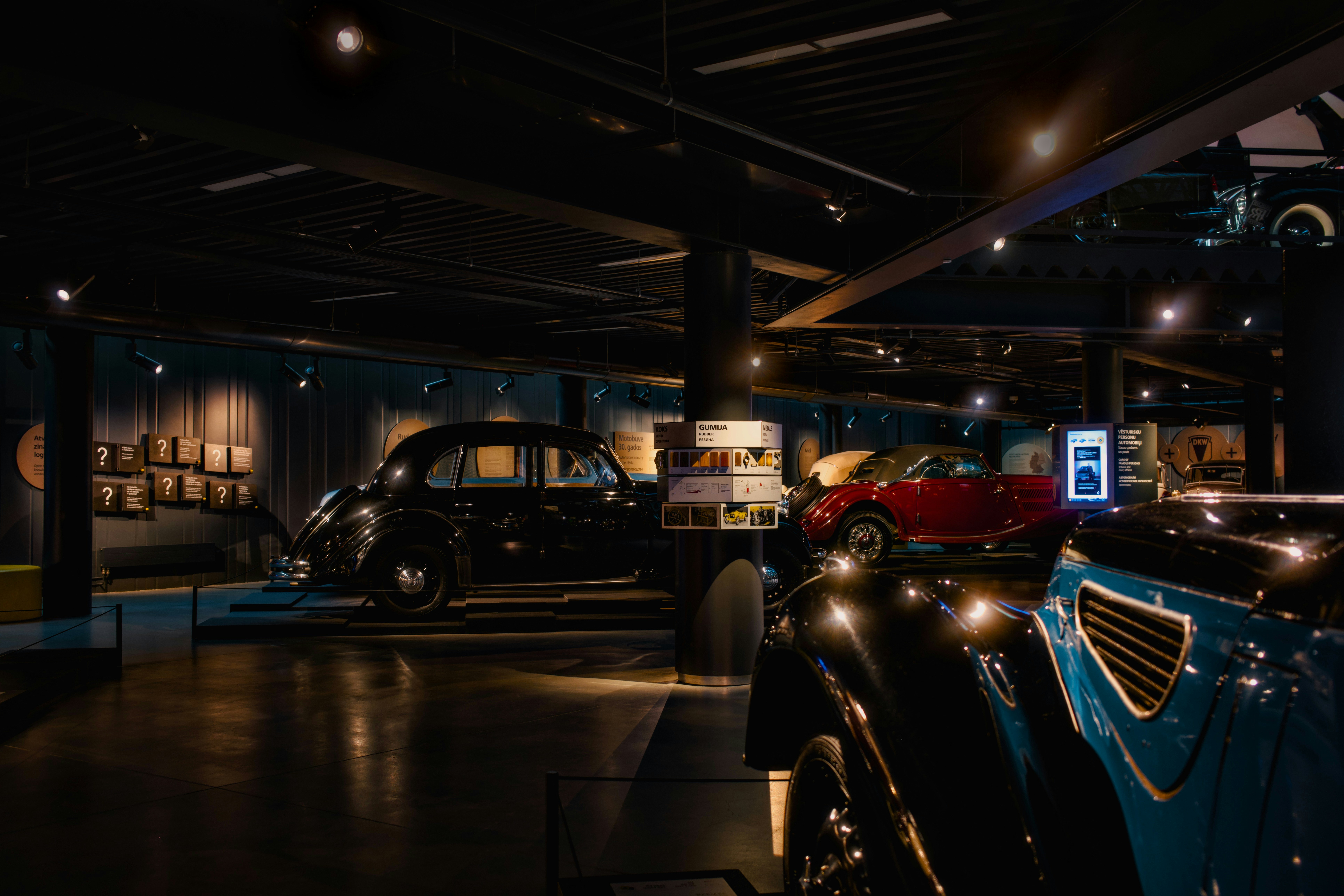 Vintage cars displayed in a dimly lit museum exhibit.