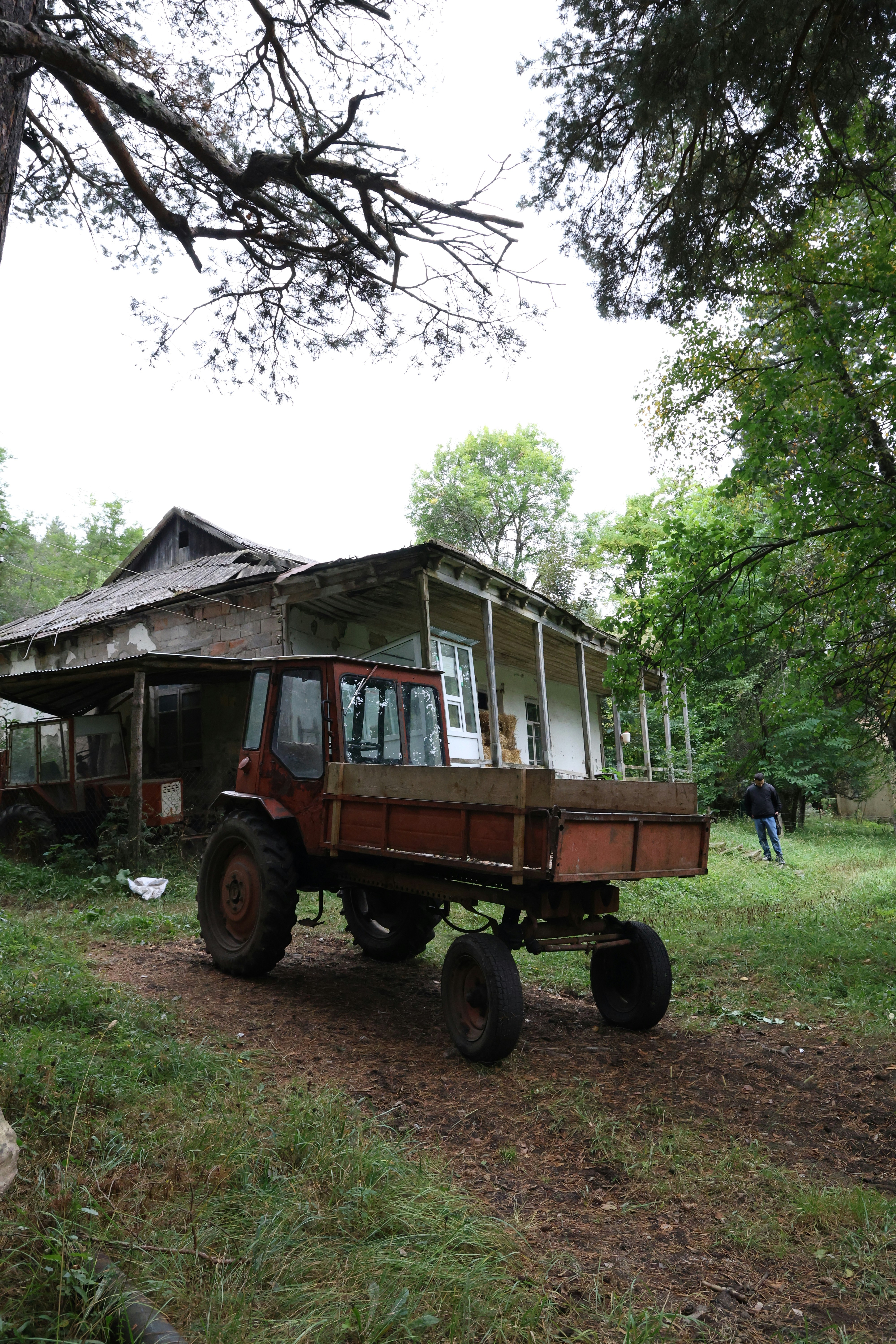 Old tractor parked beside a dilapidated rural house.