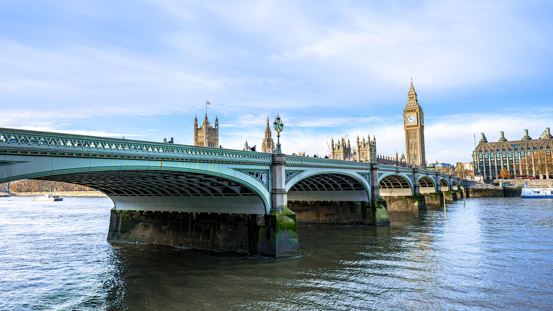 Photograph of Elizabeth Tower, the Palace of Westminster and Westminster Bridge beside the river in London.