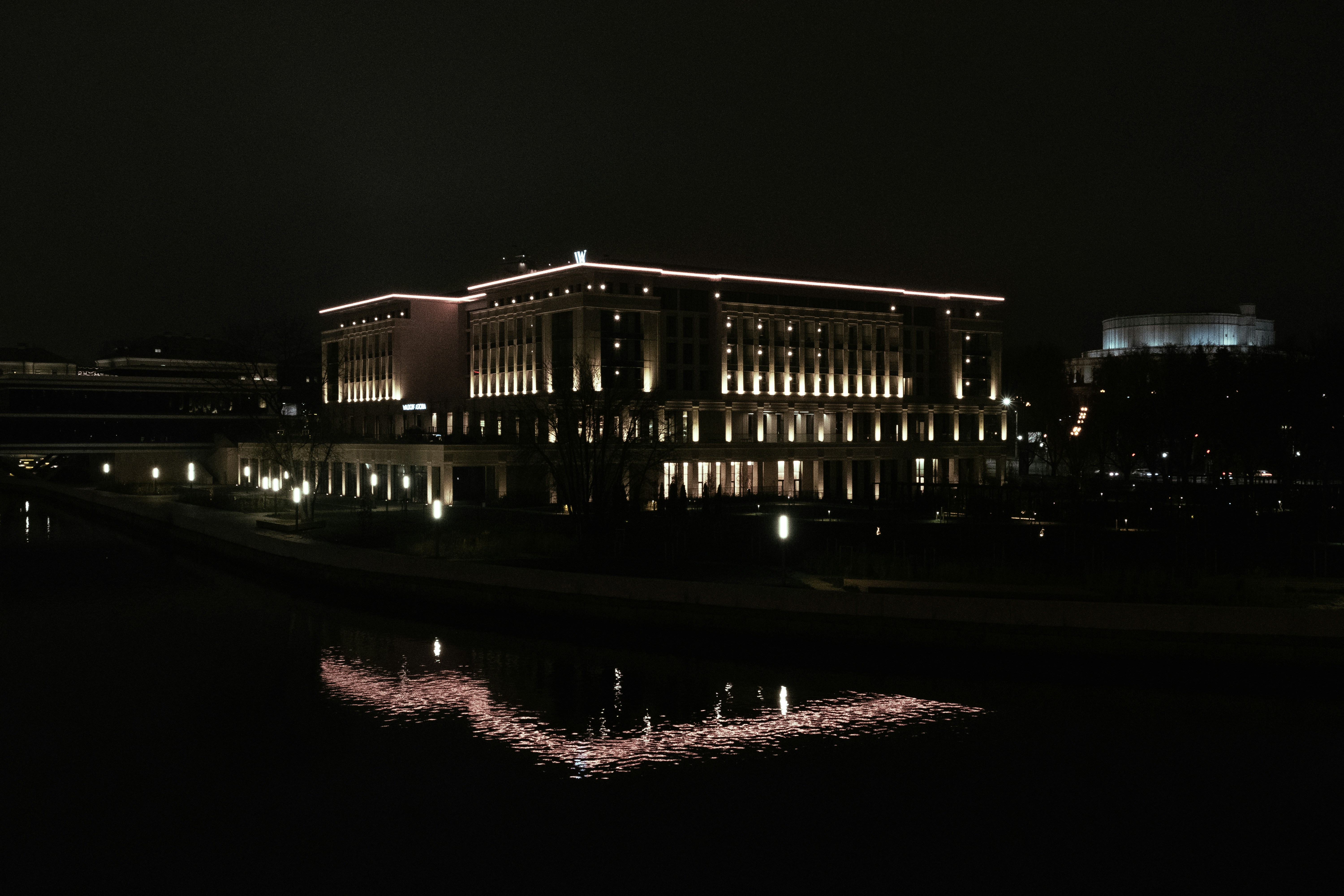 Illuminated building reflected in dark water at night.