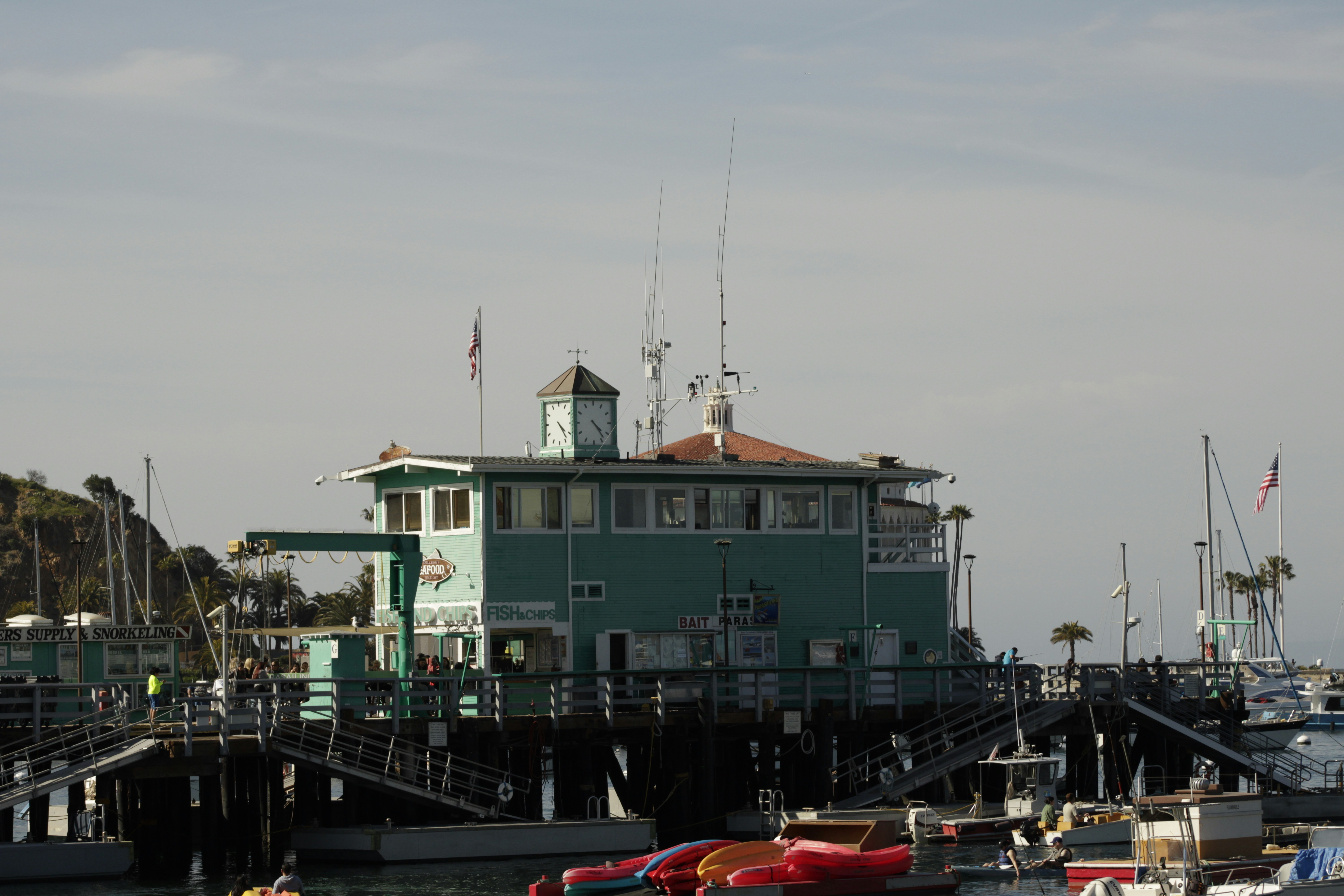 A teal building on a pier with boats nearby
