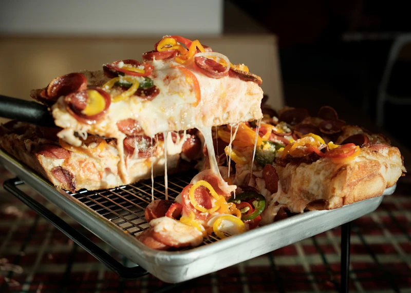 Thick, cheesy deep-dish pizza slices with a heavy cheese pull, fresh from the pan