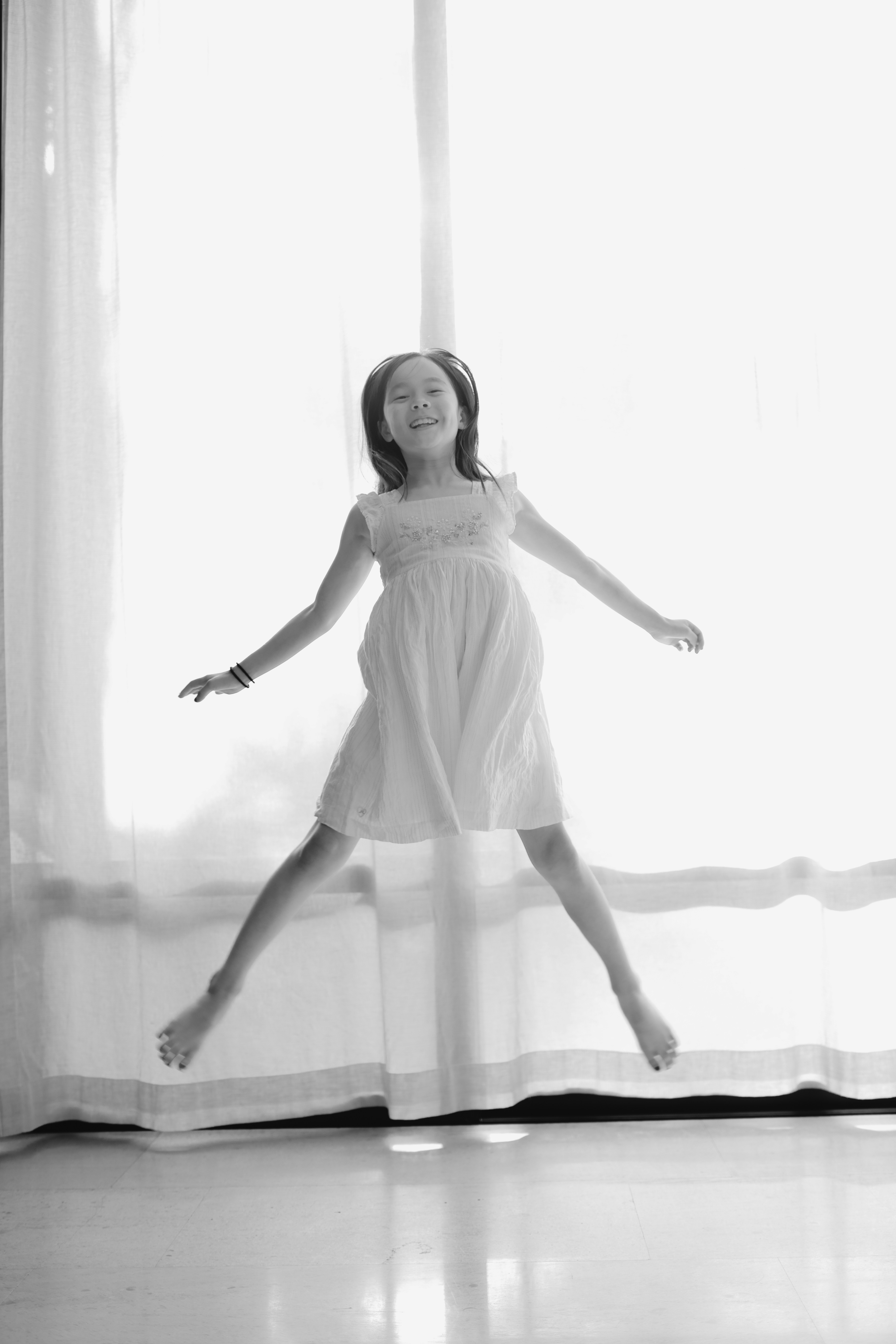 A young girl in a dress jumps joyfully.