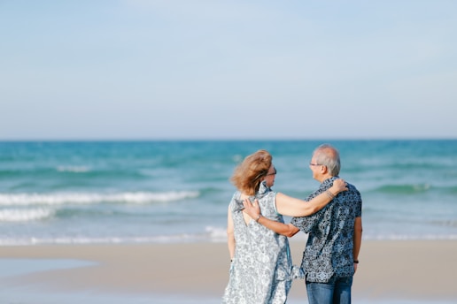 Elderly couple embracing on a sandy beach.