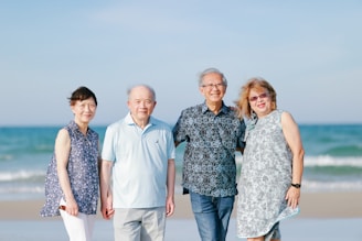 Four smiling people standing on a beach
