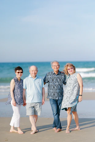 Four smiling seniors posing on a beach