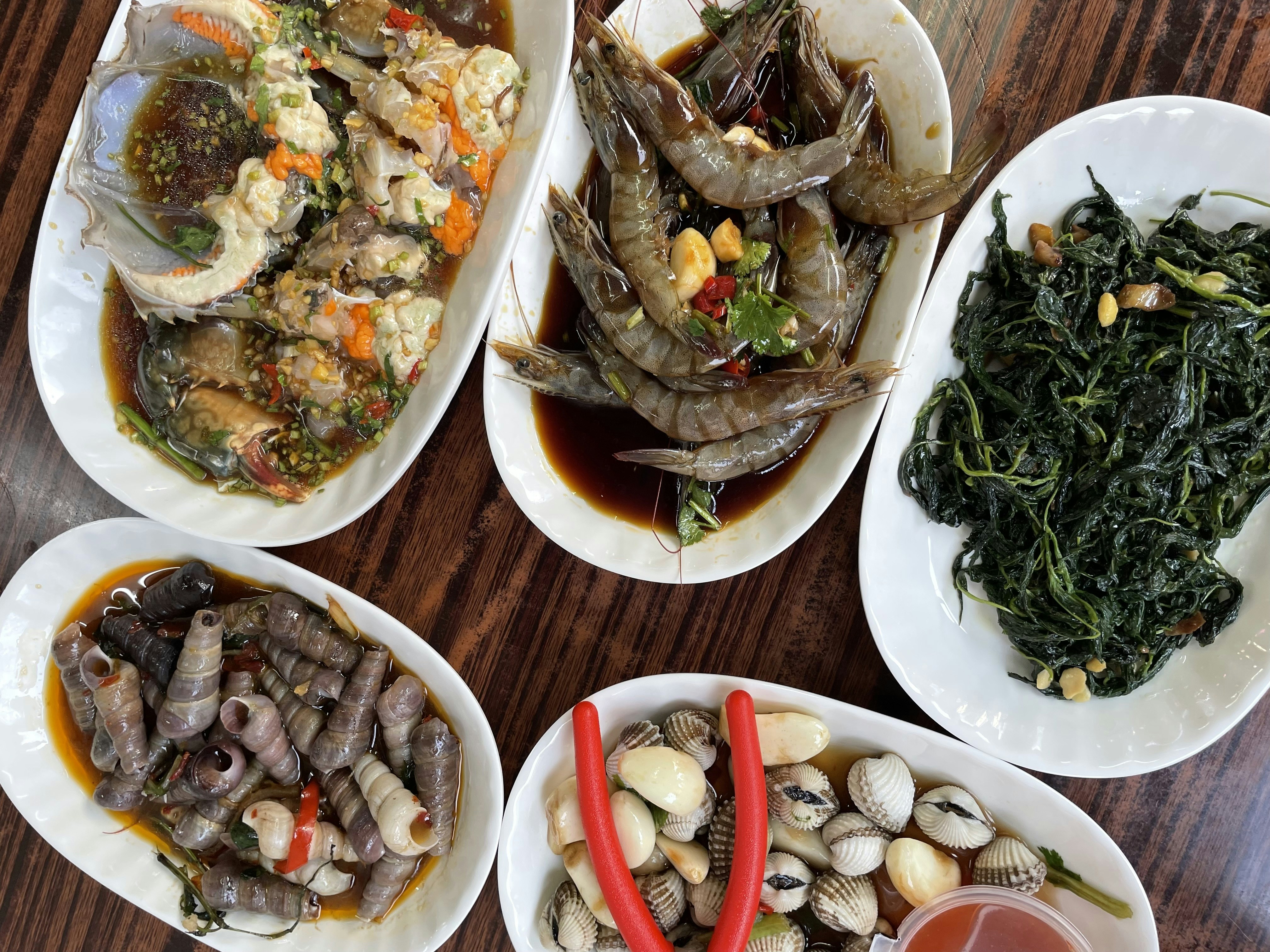 Five plates of seafood and vegetables on table