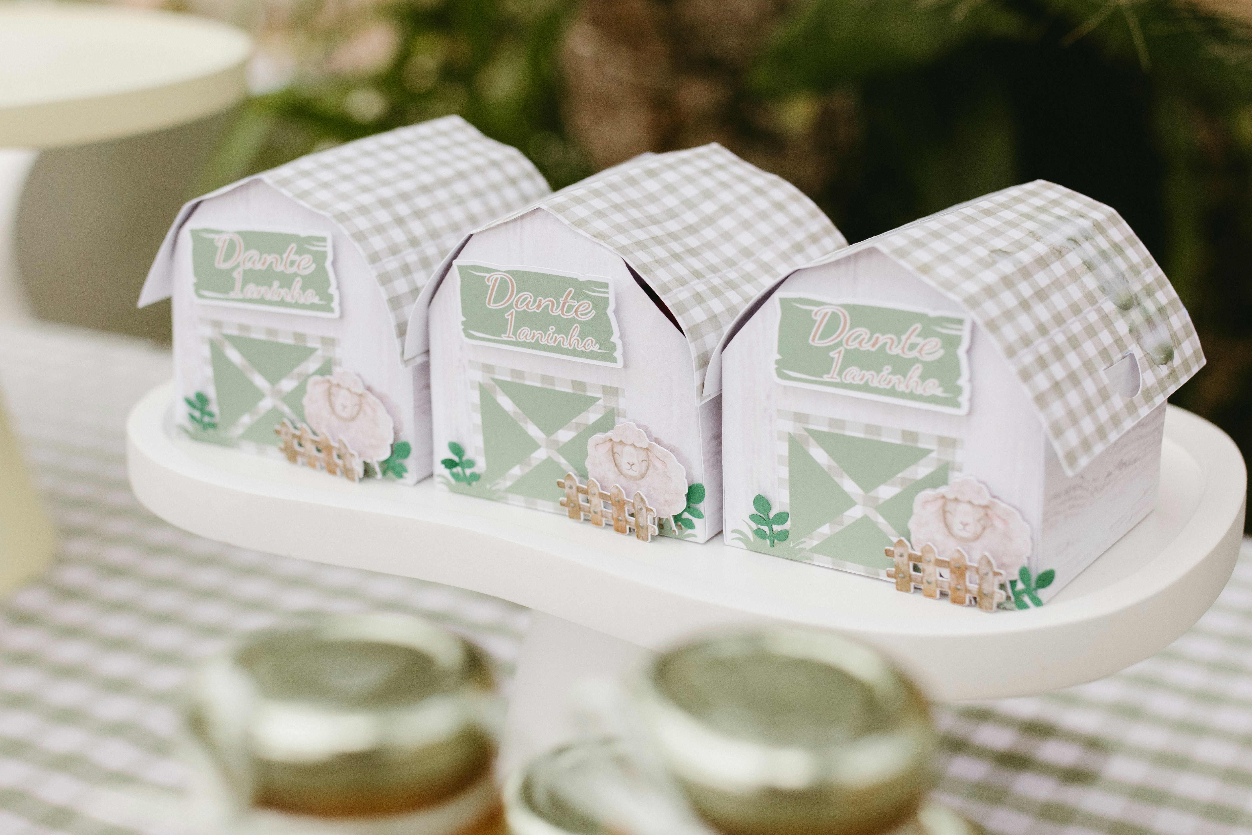 Three barn-shaped party favors on a cake stand.