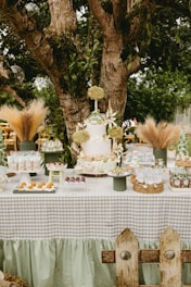 A dessert table set up outdoors under a tree.