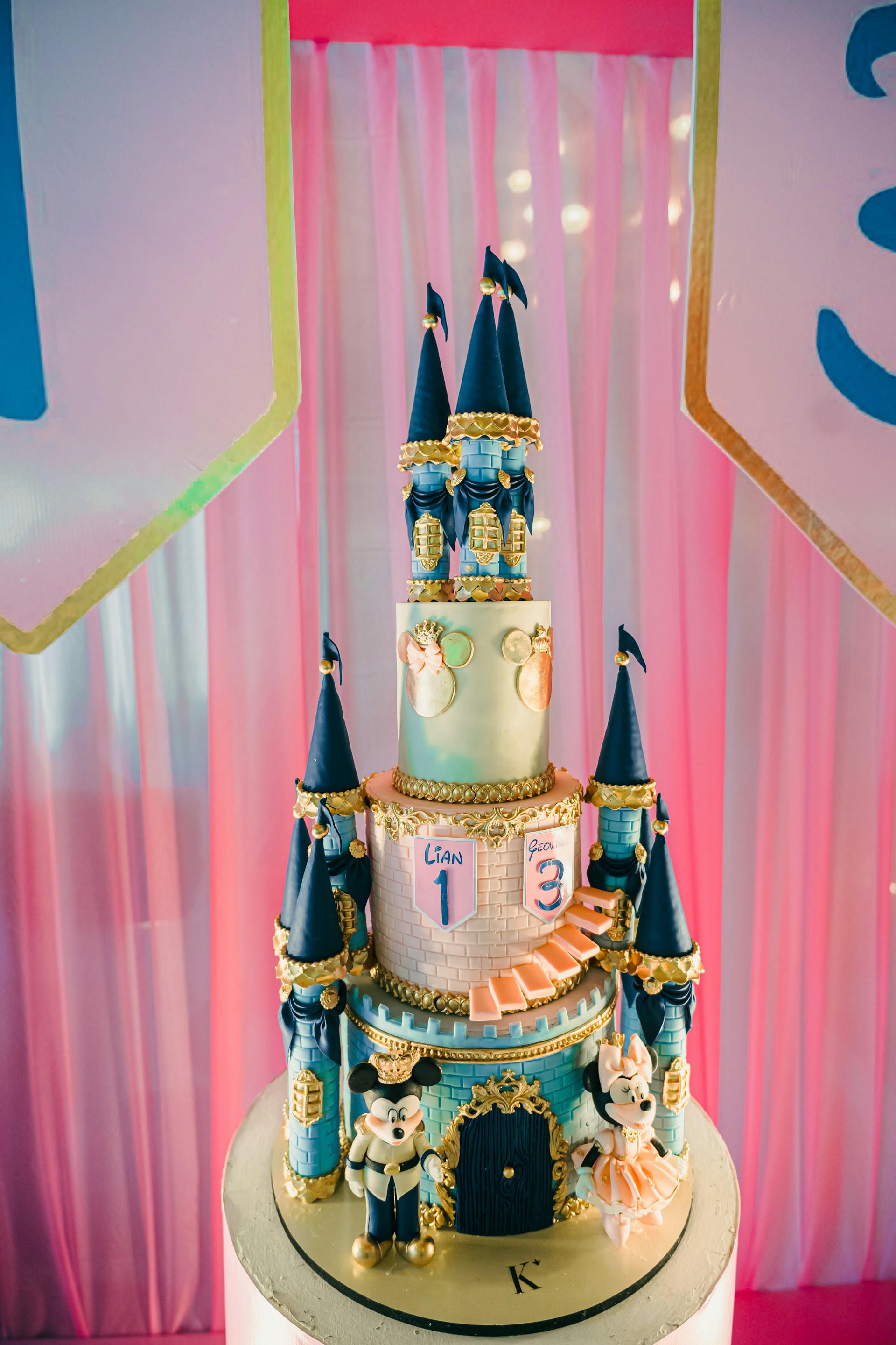 A multi-tiered castle cake with mickey and minnie mouse.