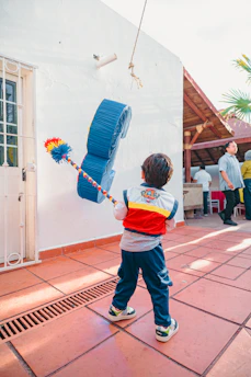 Boy hitting a blue piñata with a stick