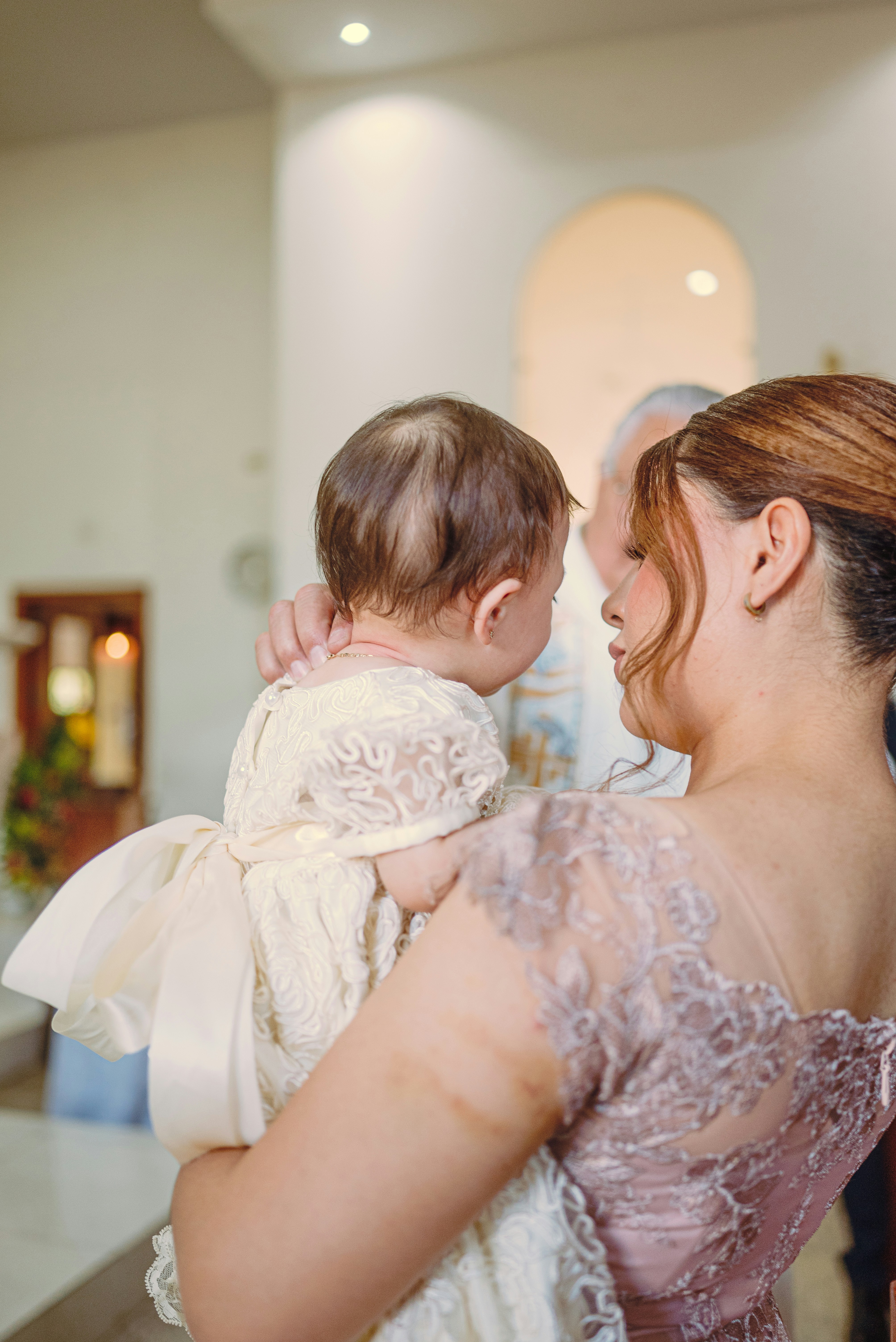 Die Mutter hält das Baby in einem Taufkleid