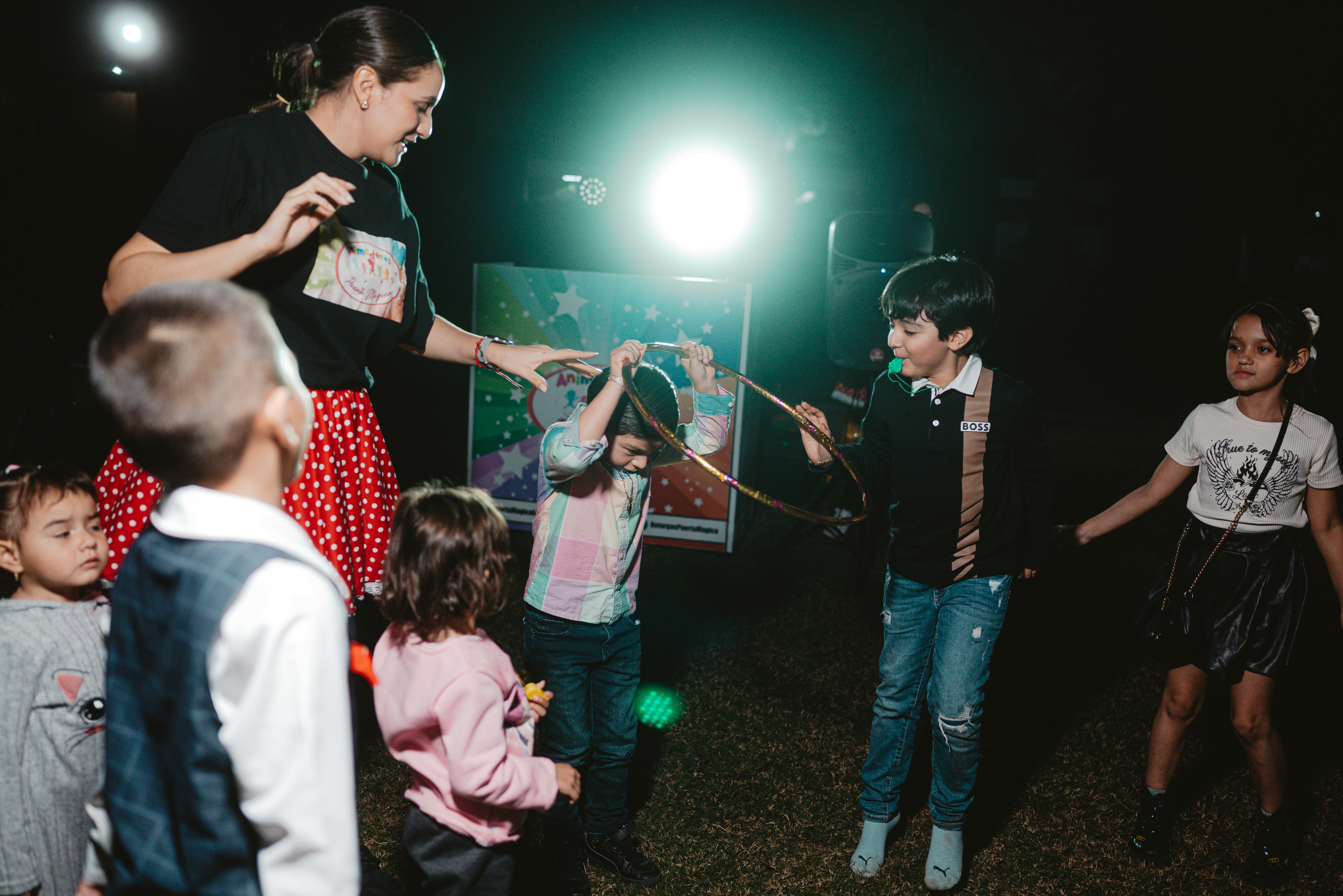 Children and adult playing with a hoop outdoors at night