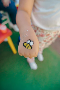 Child's hand with a painted bee design.