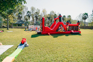 A red inflatable castle bounce house on a grassy lawn.