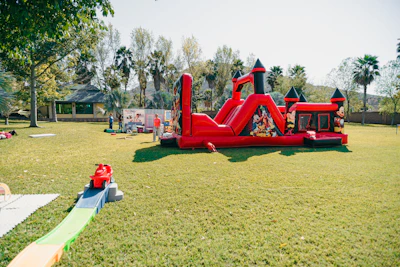 A red inflatable castle bounce house on a grassy lawn.