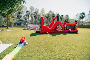 A red inflatable castle bounce house on a grassy lawn.
